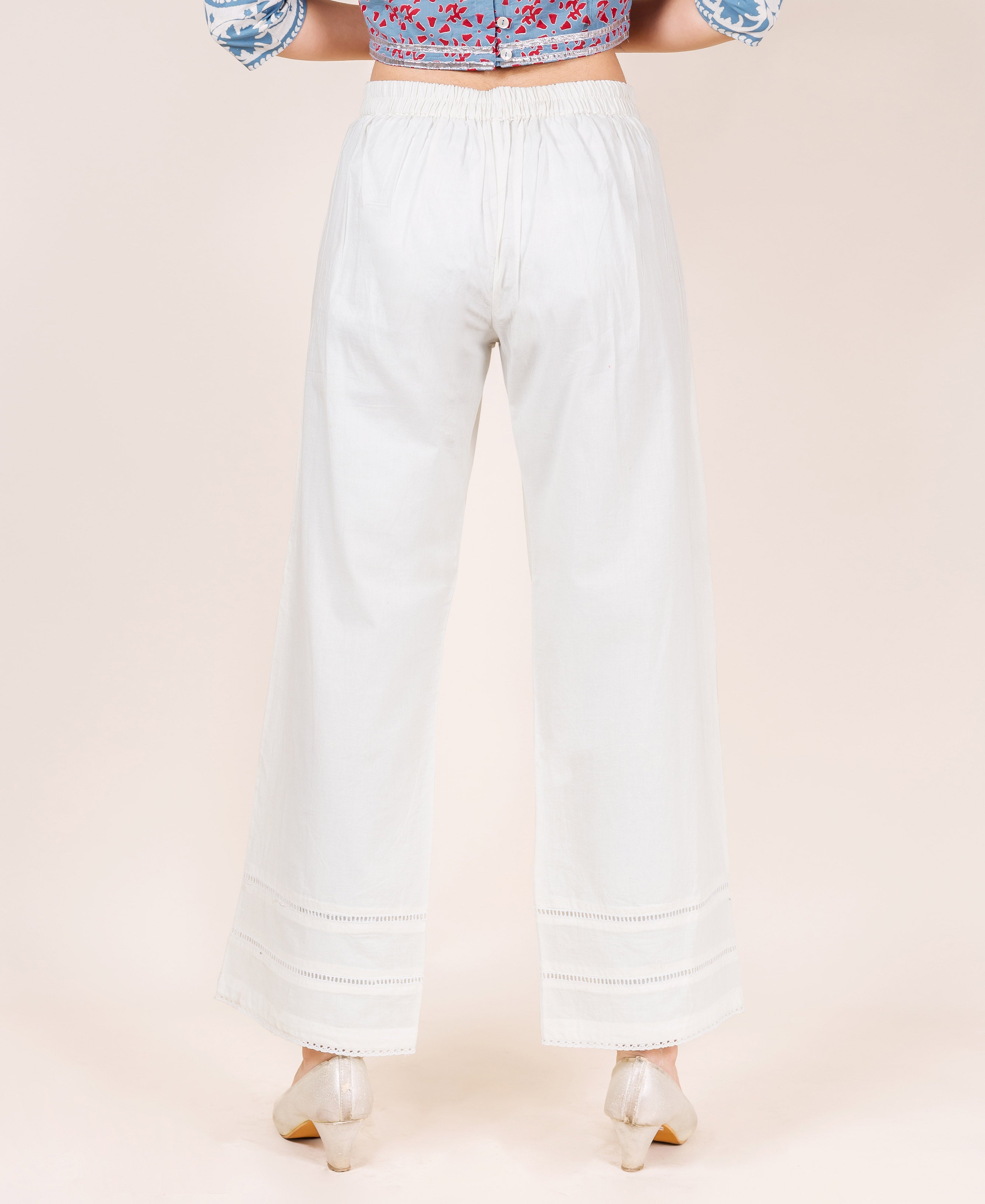 Model wearing white palazzo pants with lace trim.