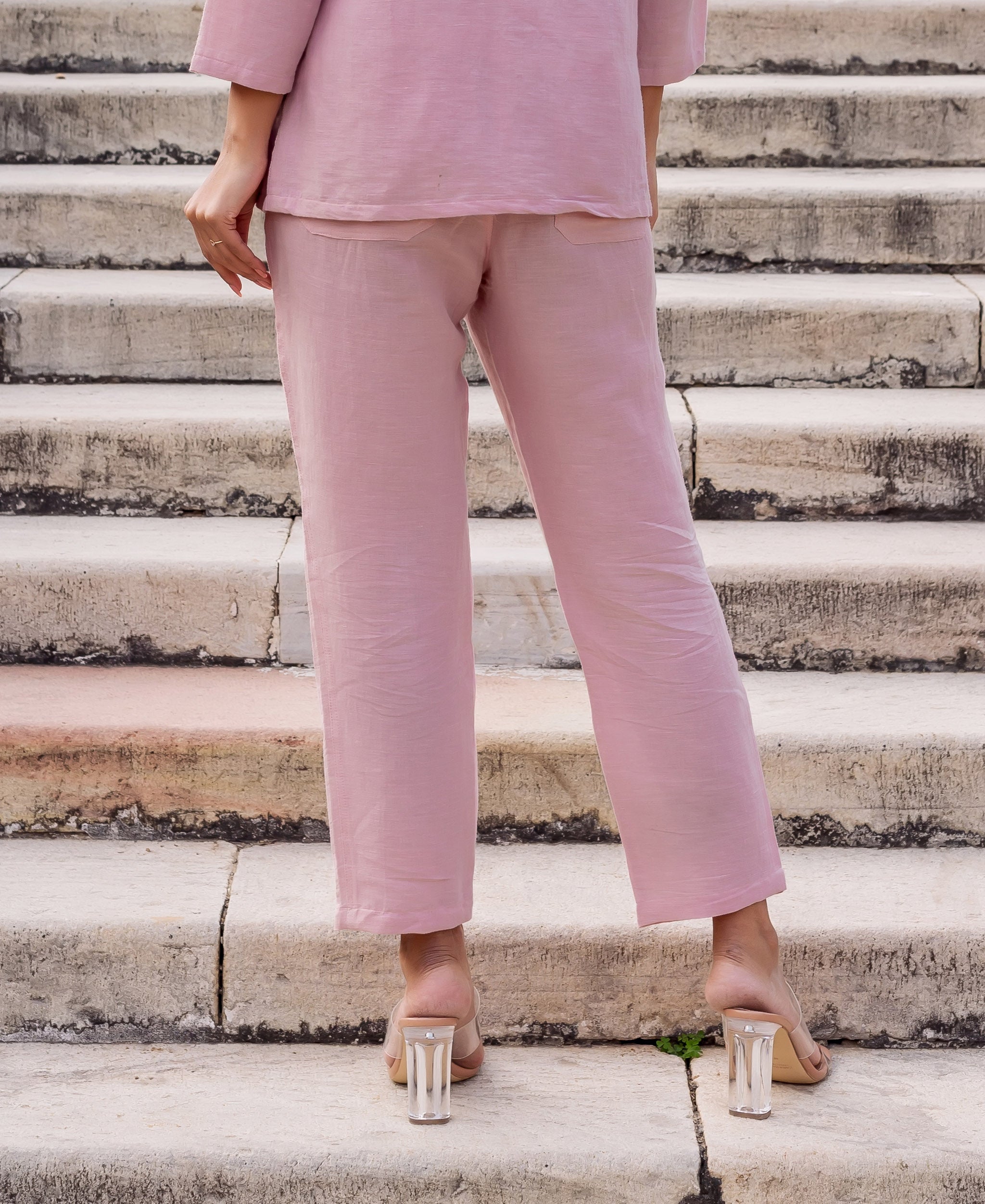 Back view of model in solid flamingo pink linen pants and matching top.