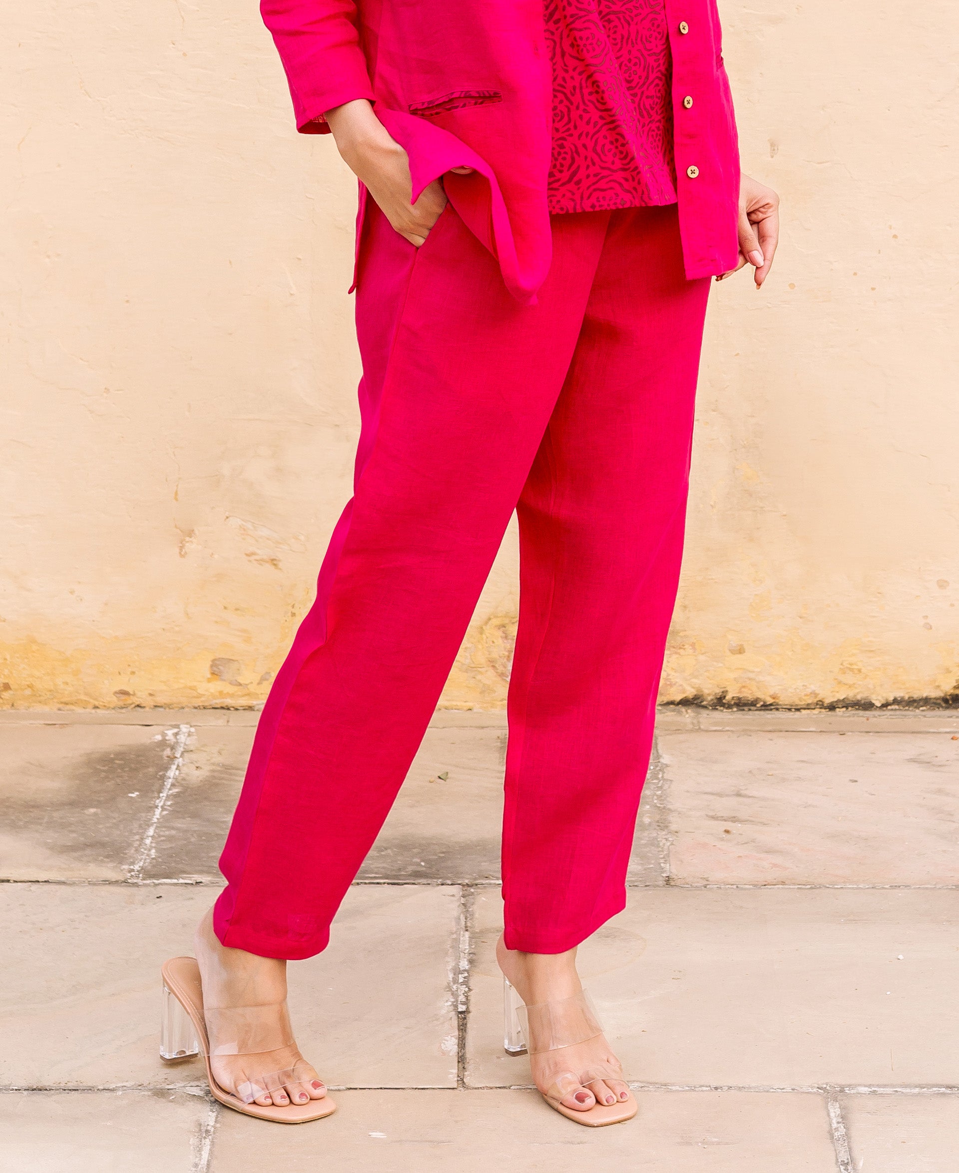 Lower body shot of a model wearing ruby pink linen solid pants and clear heels.