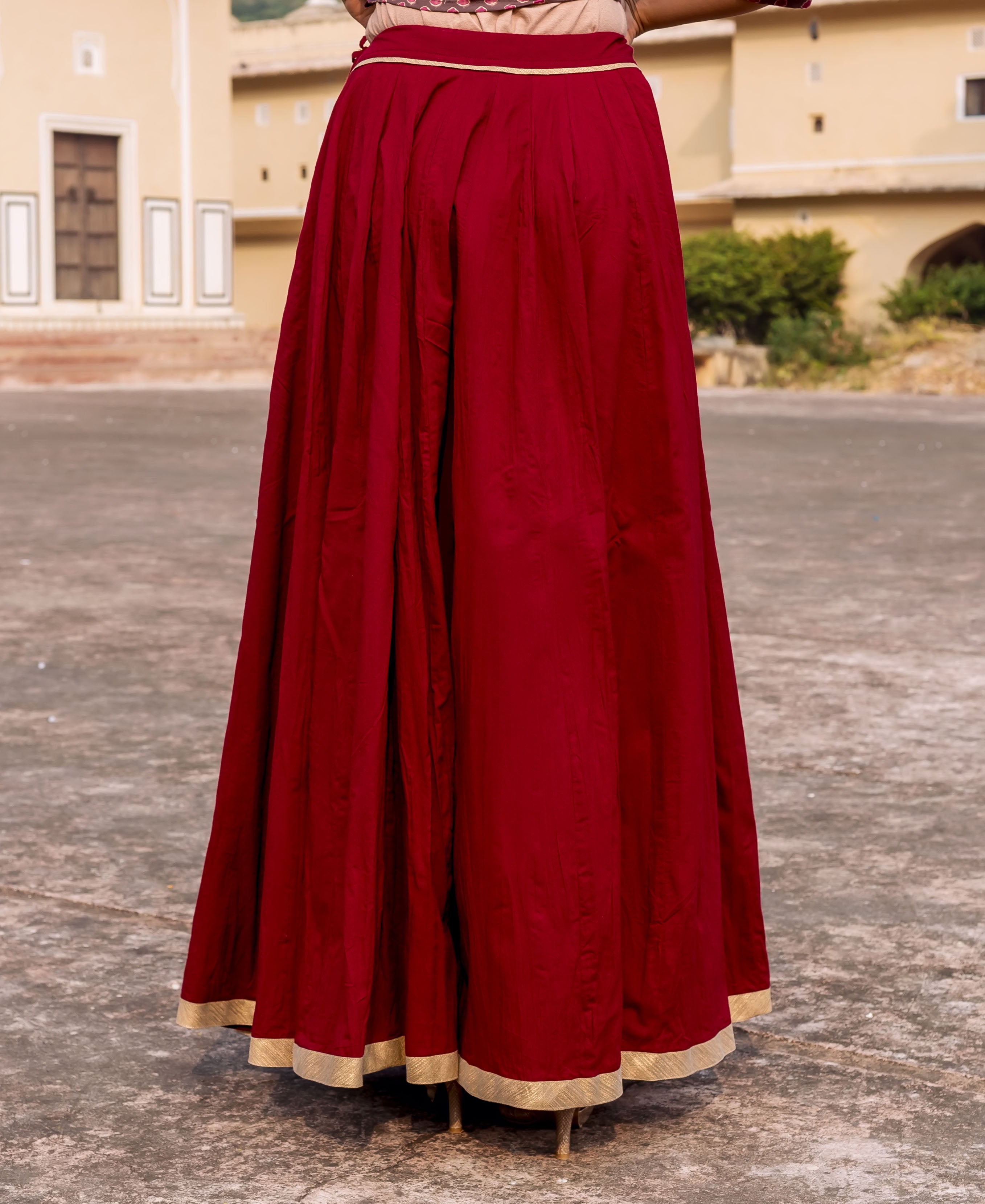 Maroon pleated skirt with golden gotta trims, worn by model.