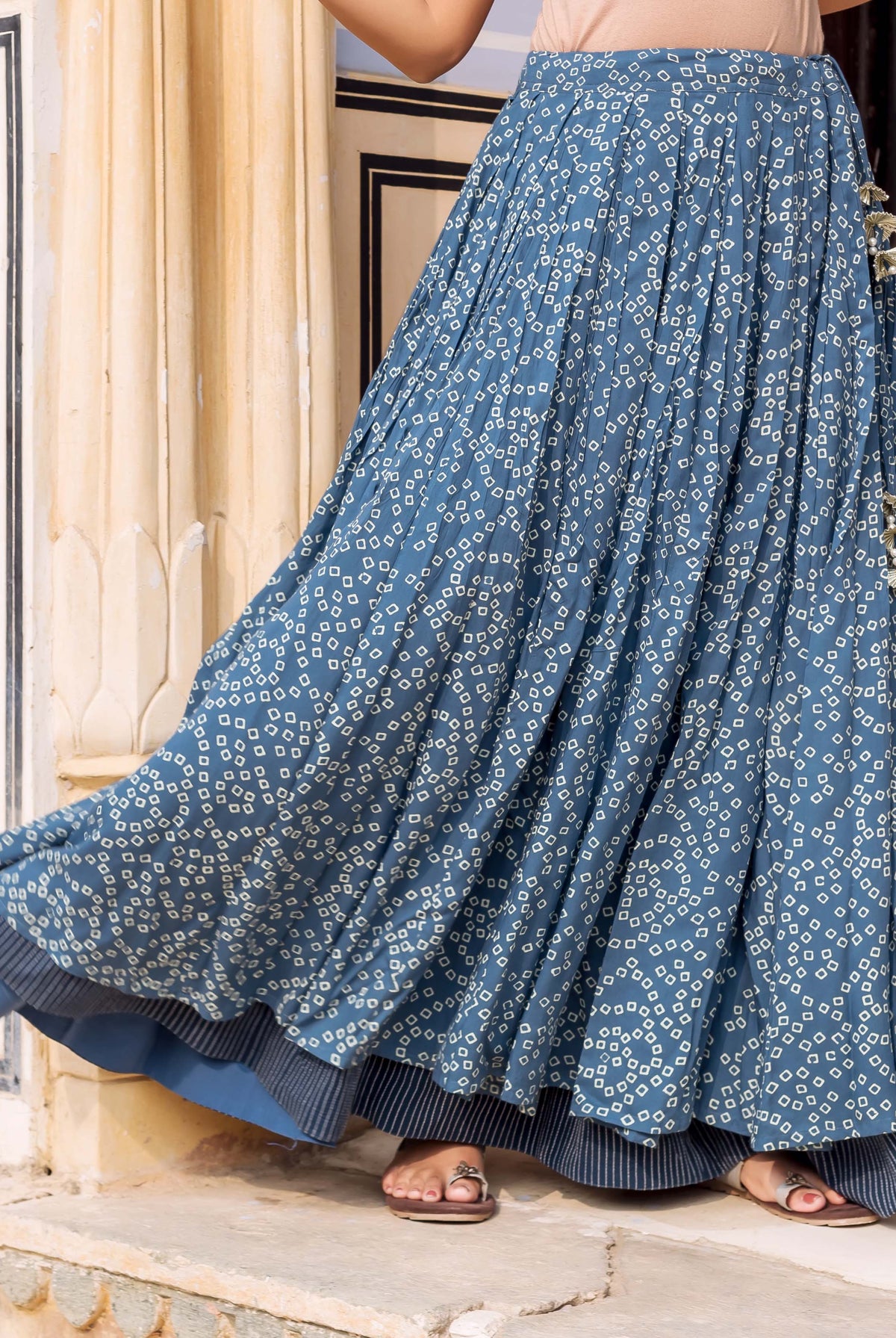 Indigo blue bandhej printed double-layered pleated skirt with tassels on a model.