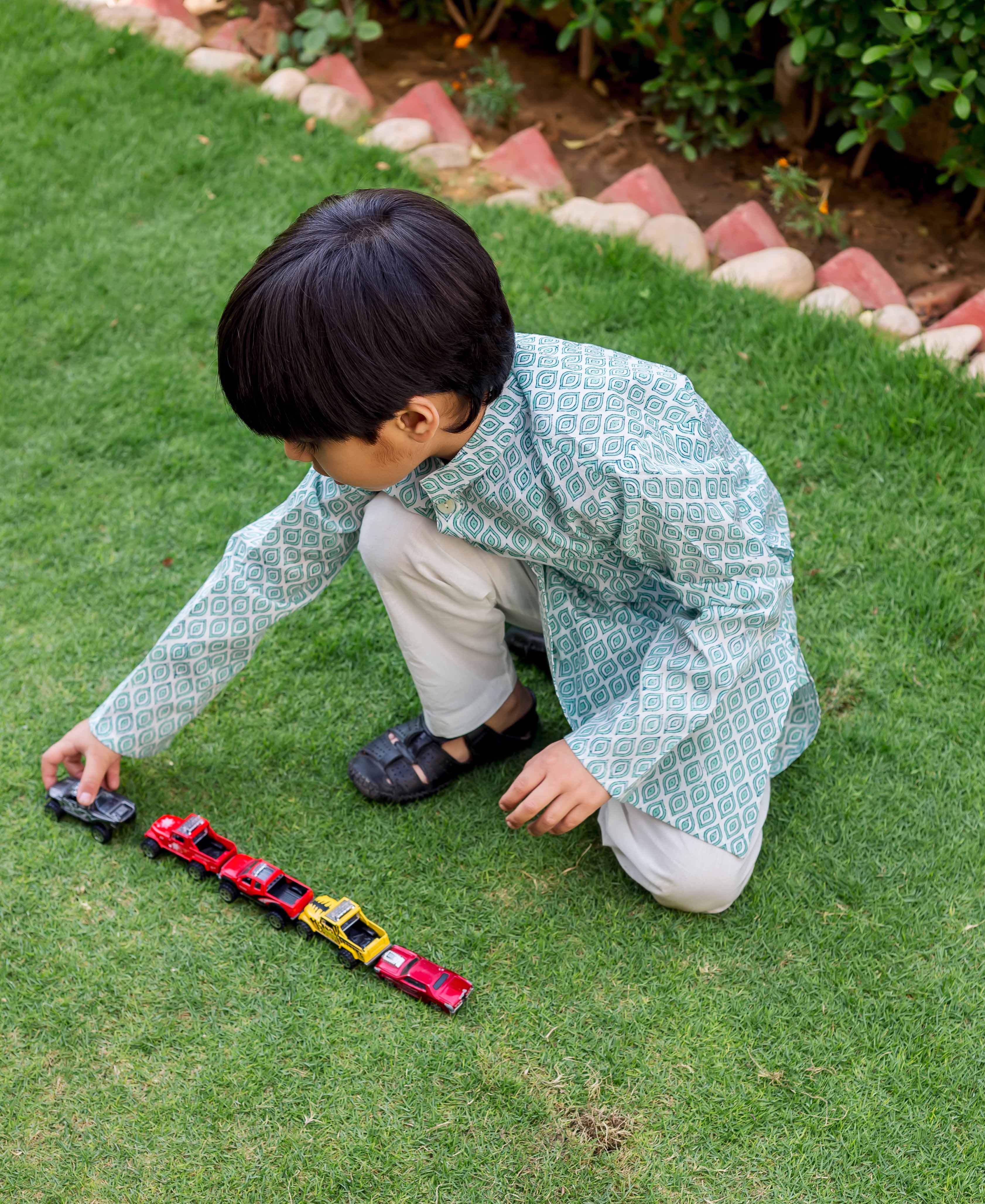 Child model in light green and white block printed kurta pajama, crouching.