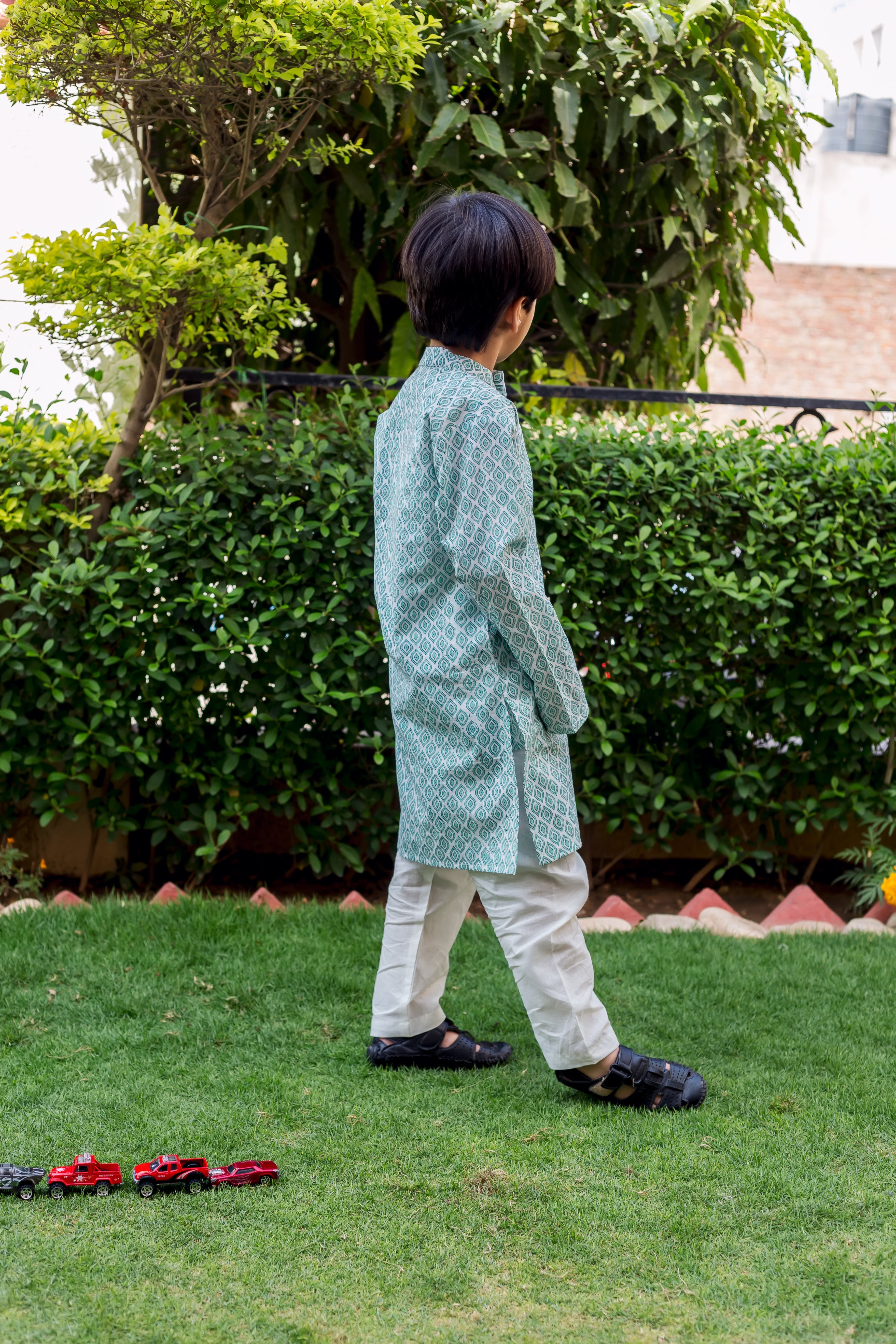 Child model, side view, wearing light teal and white block printed kurta pajama set.