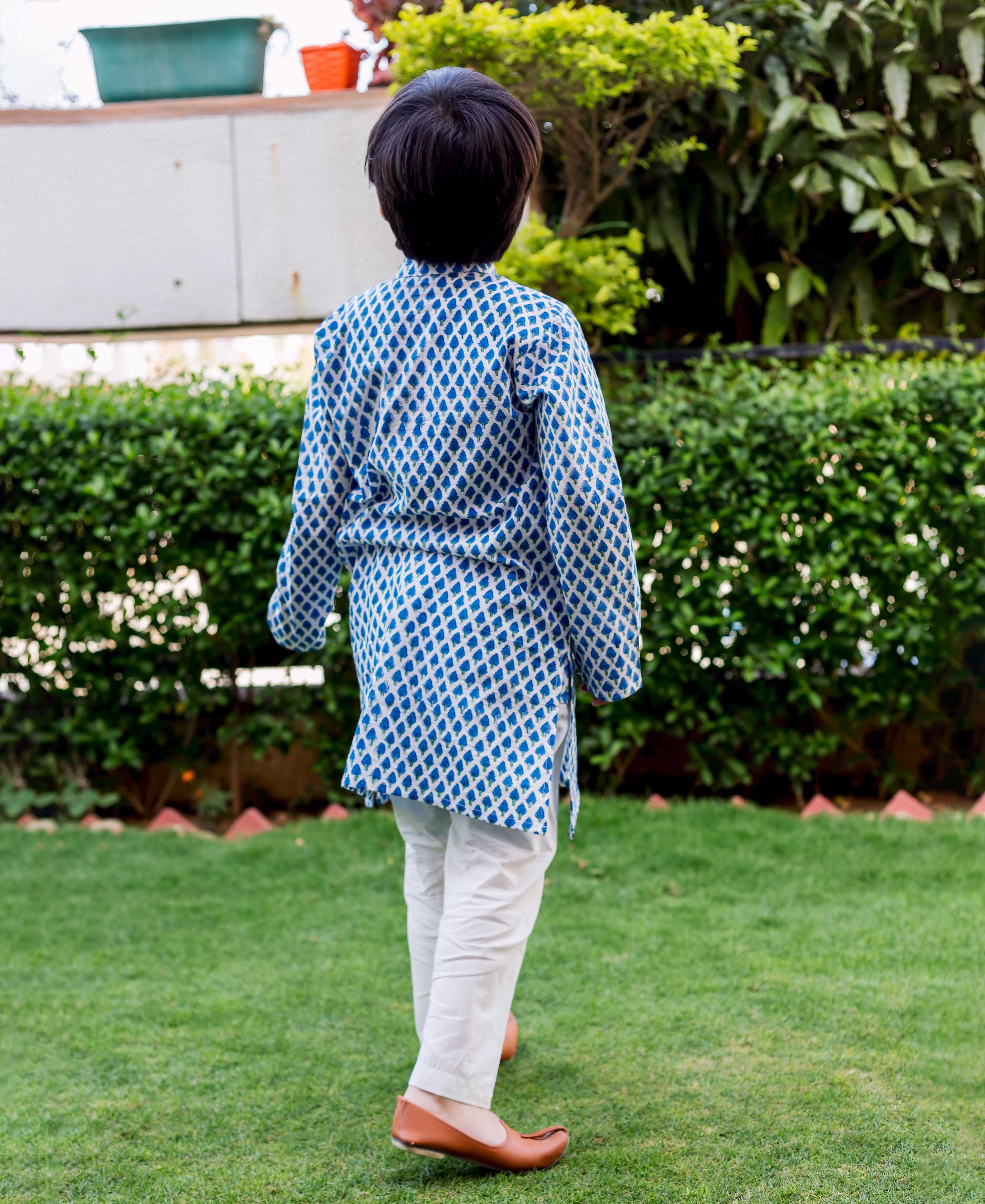 Back view of child model in a full blue and white booti printed kurta pajama set.