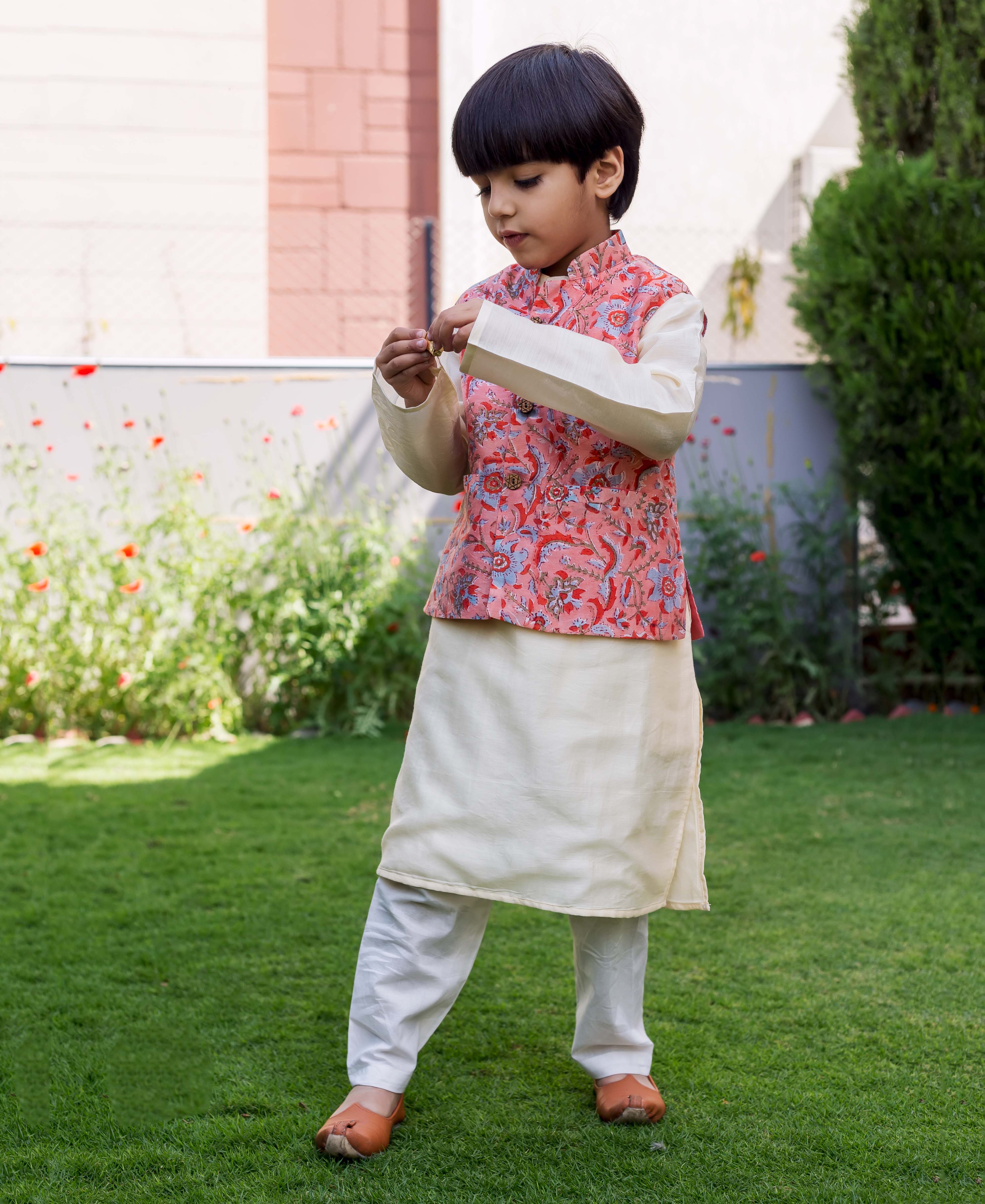 Young boy model wearing a peach chanderi waistcoat with red and blue floral print.