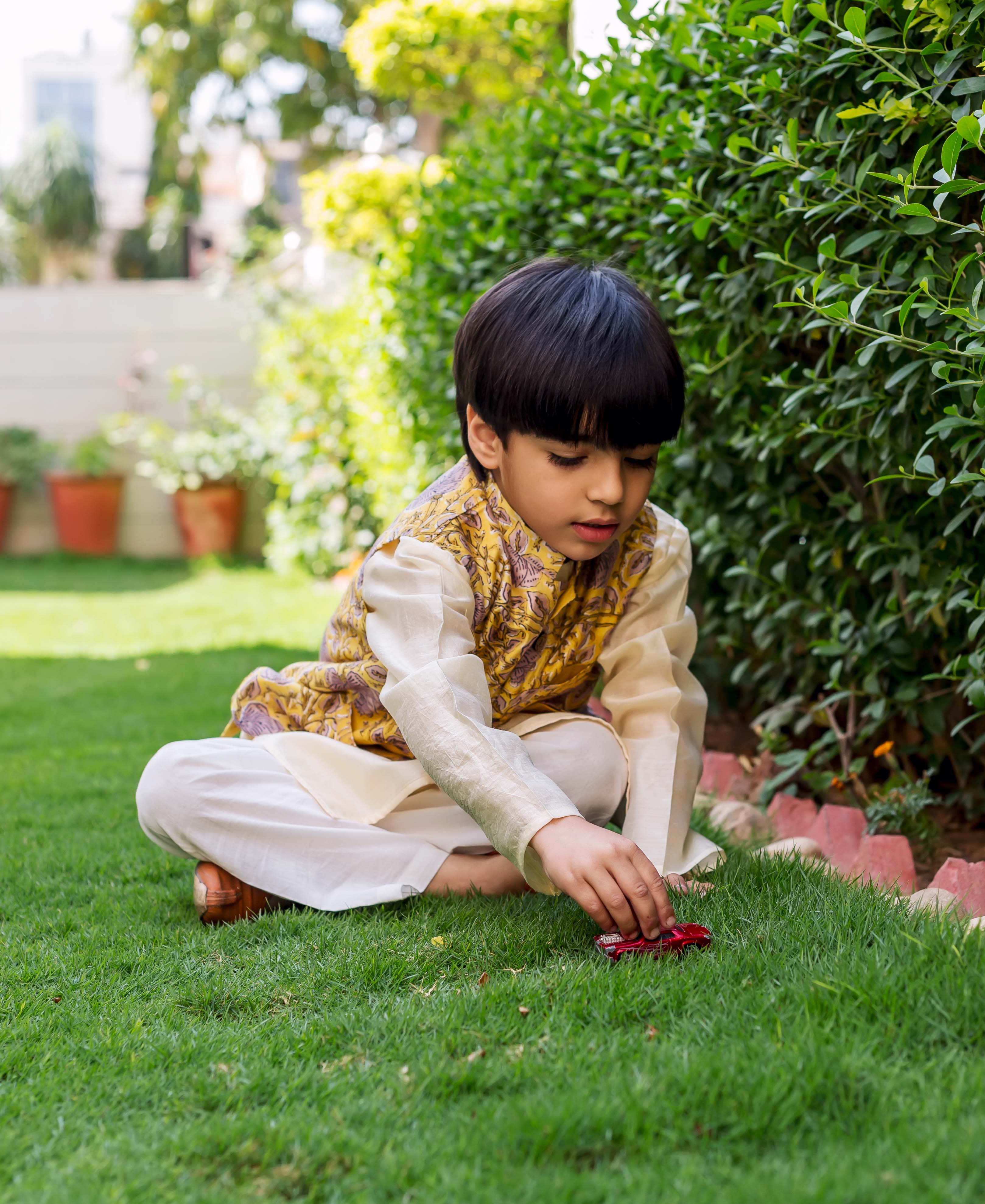 Young boy in yellow and grey hand-block printed waistcoat and cream kurta.