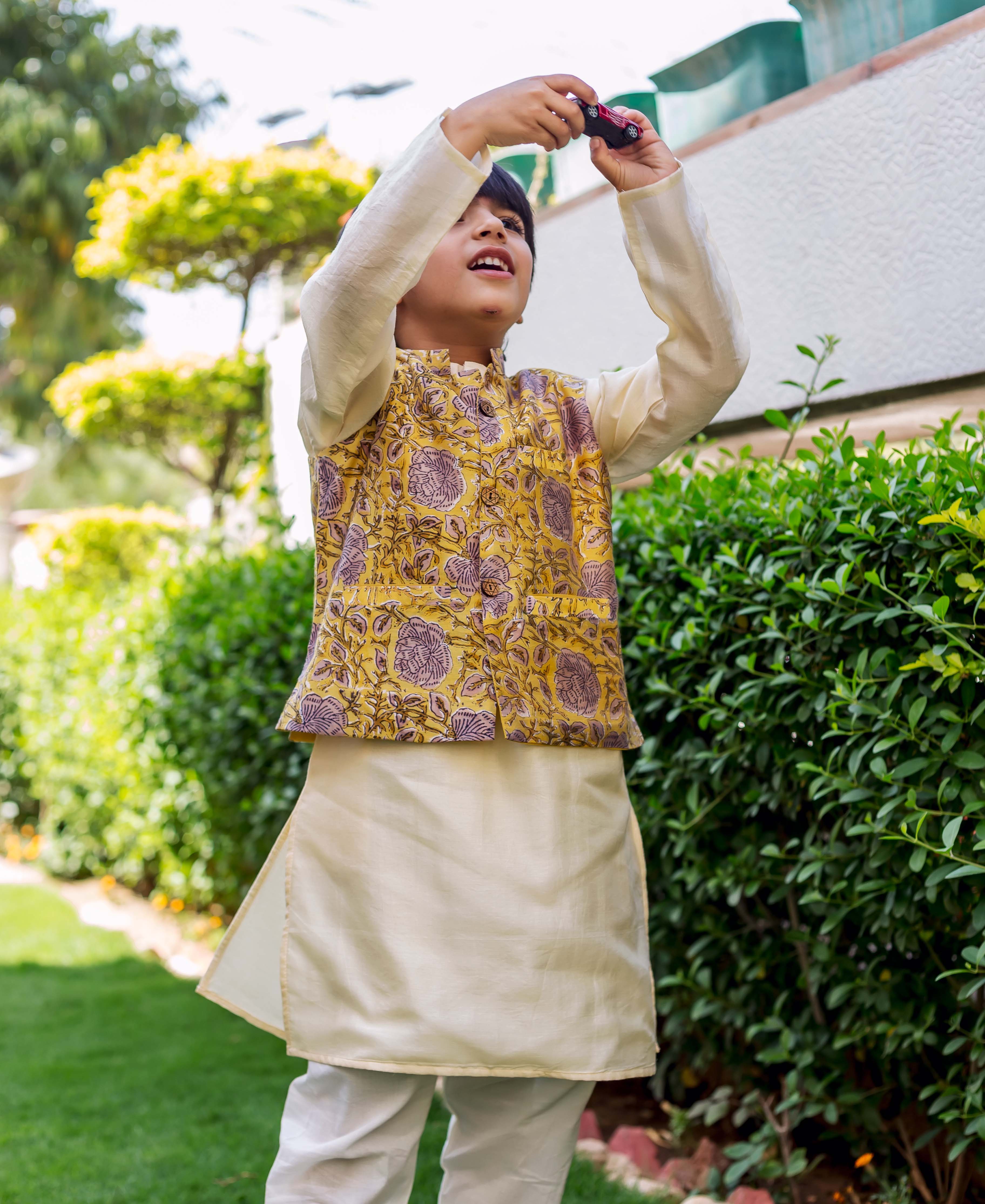 Young boy in cream kurta and yellow floral block-printed waistcoat, front view.