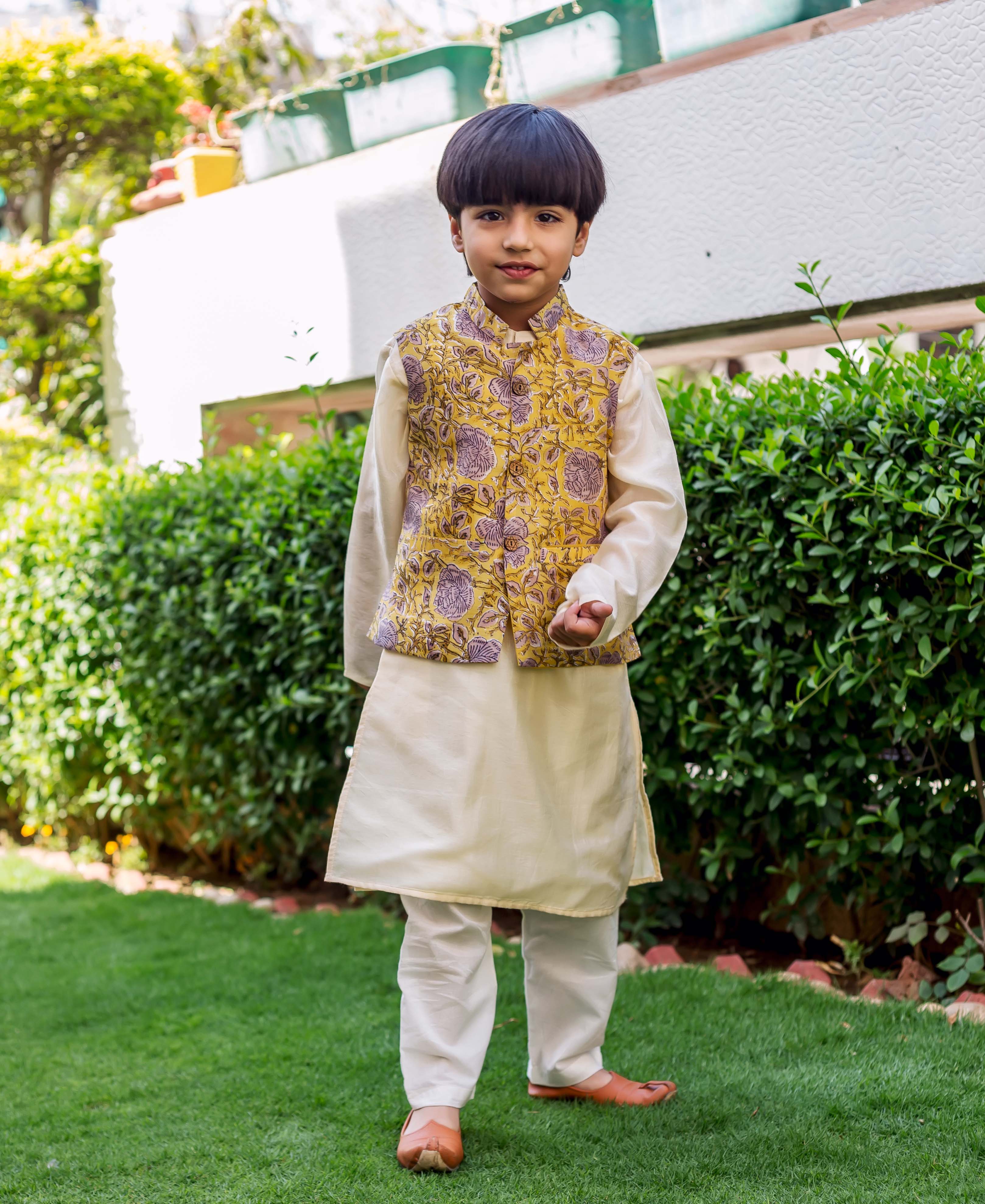 Front full-body of child model in cream kurta pajama with yellow hand-block-printed floral waistcoat.