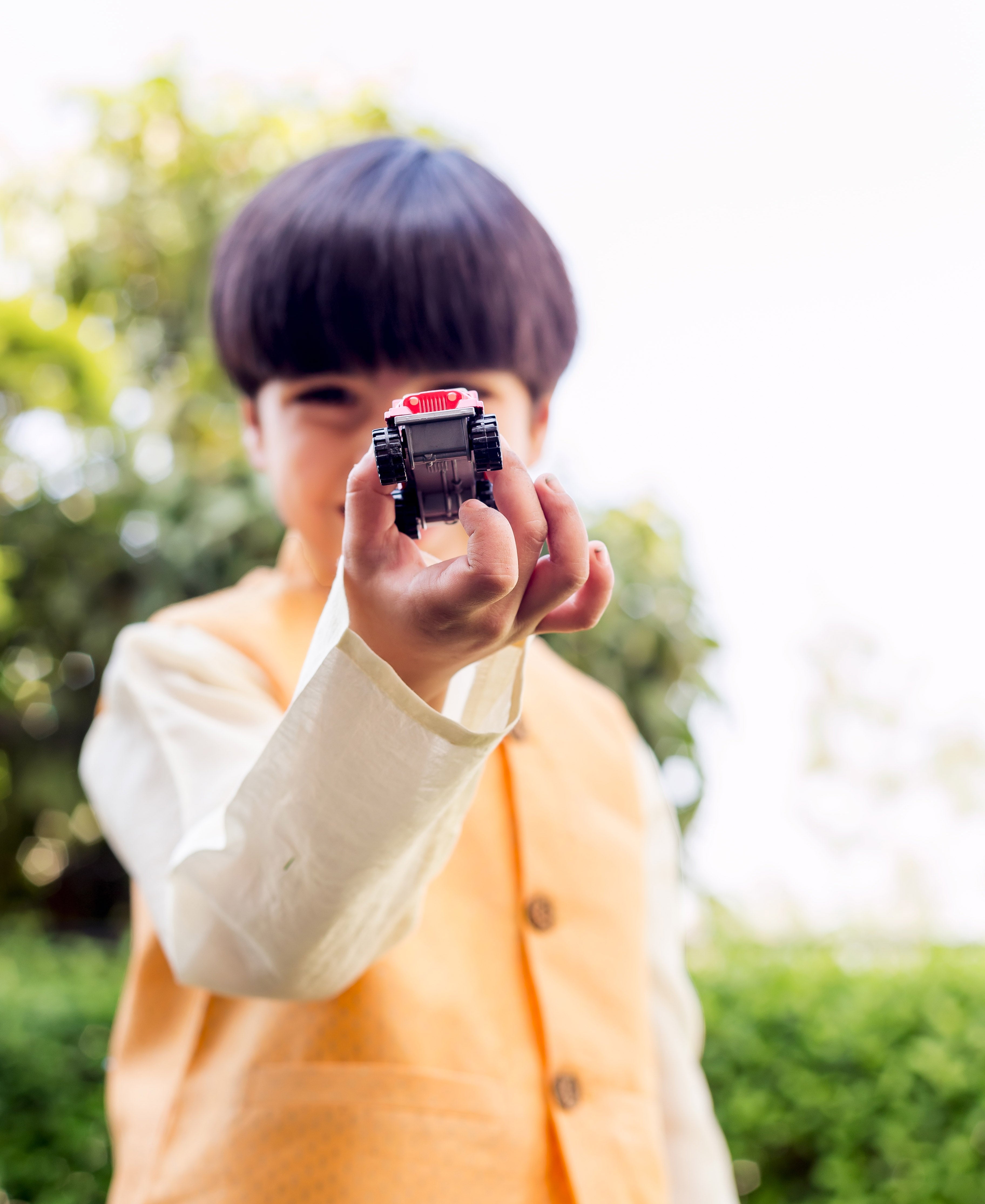 Front view of a boy wearing a yellow waistcoat with a very subtle pattern.