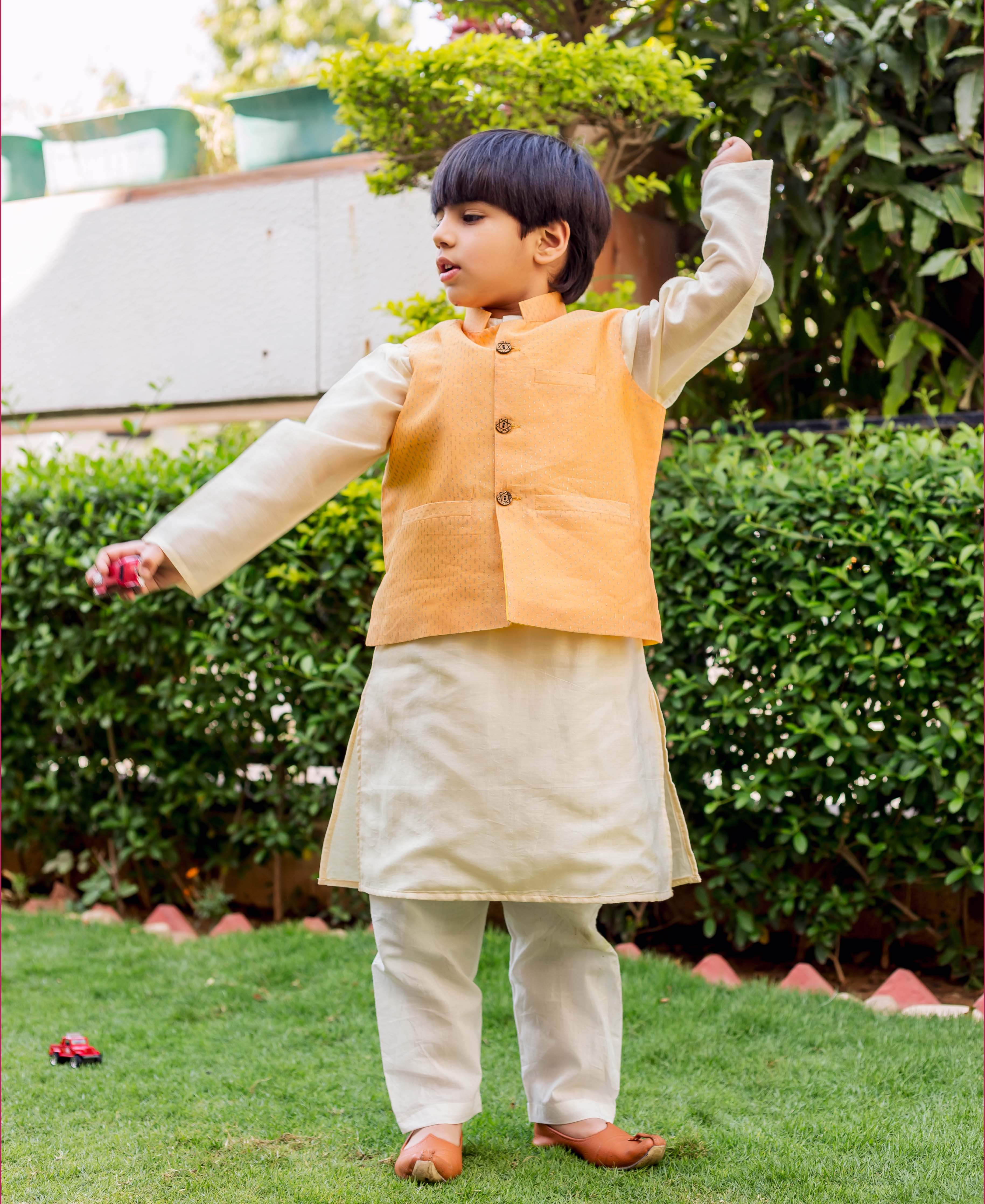 Young boy wearing a yellow hand-block printed Chanderi waist coat over a cream kurta set.