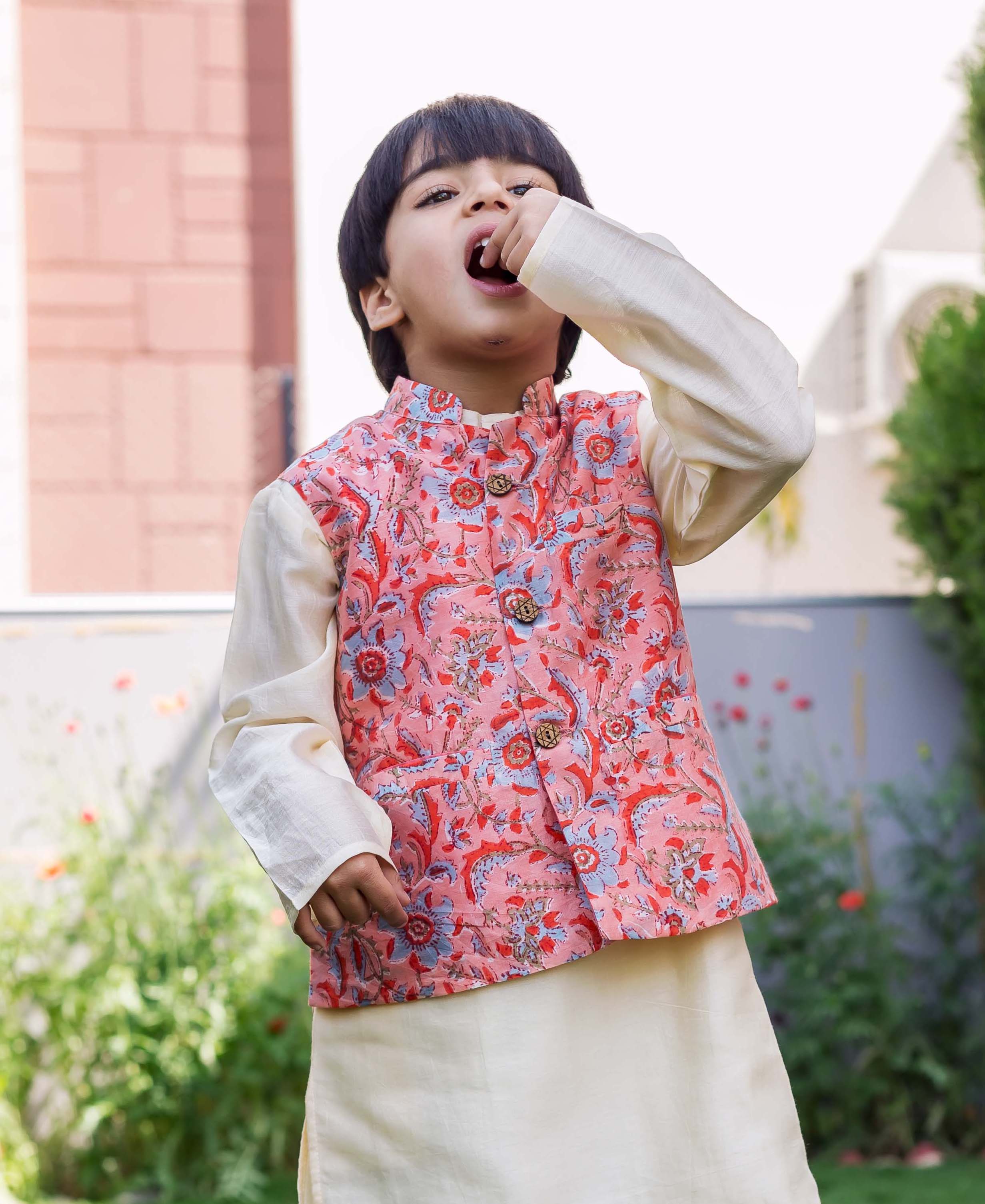 Front view of young boy in peach Chanderi waistcoat with blue and red floral print.