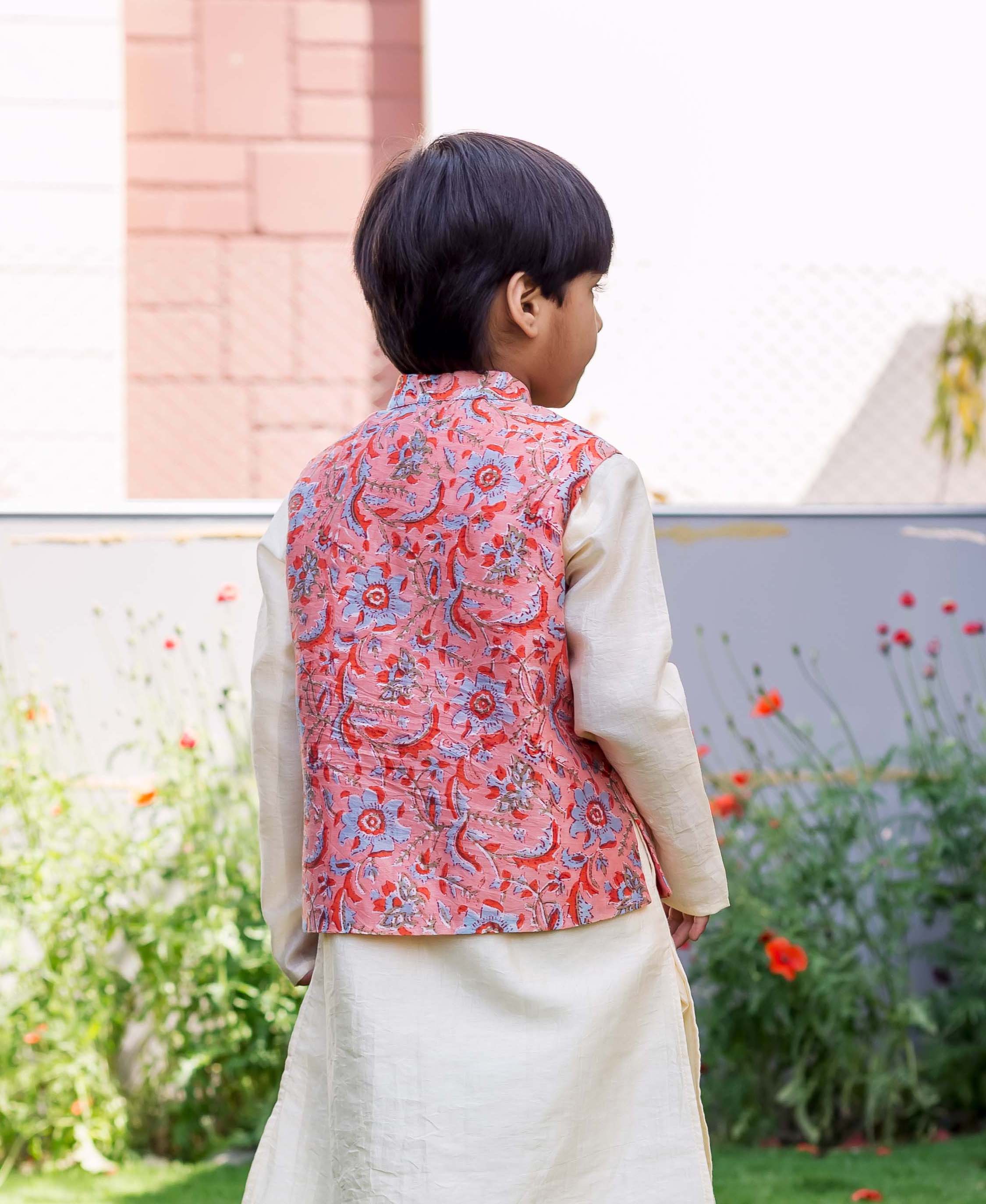 Back view of child wearing a peach Chanderi hand-block printed waistcoat over cream kurta.