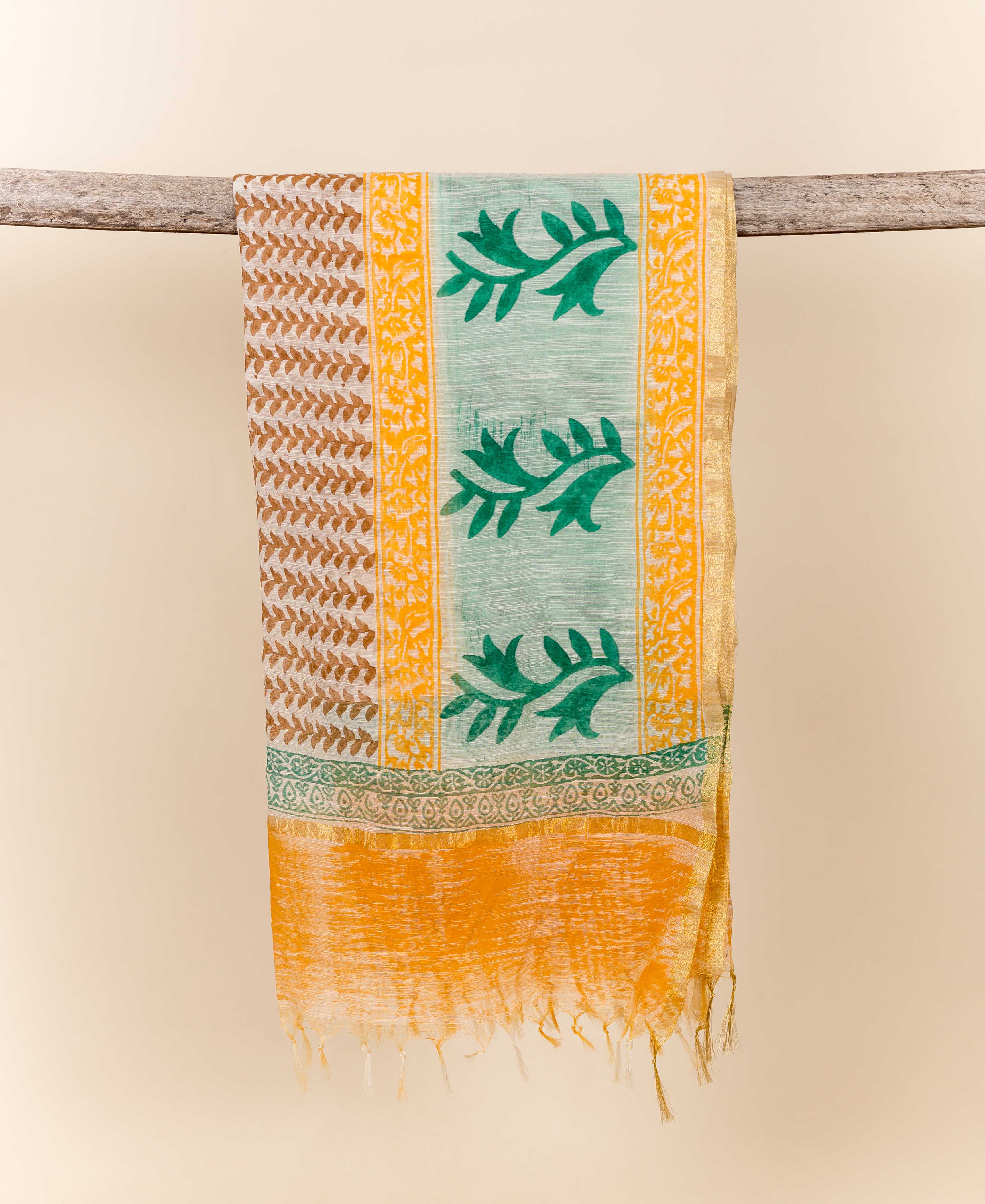 Hand-block-printed yellow and green dupatta with leaf and floral motifs, fringed, draped on a branch.
