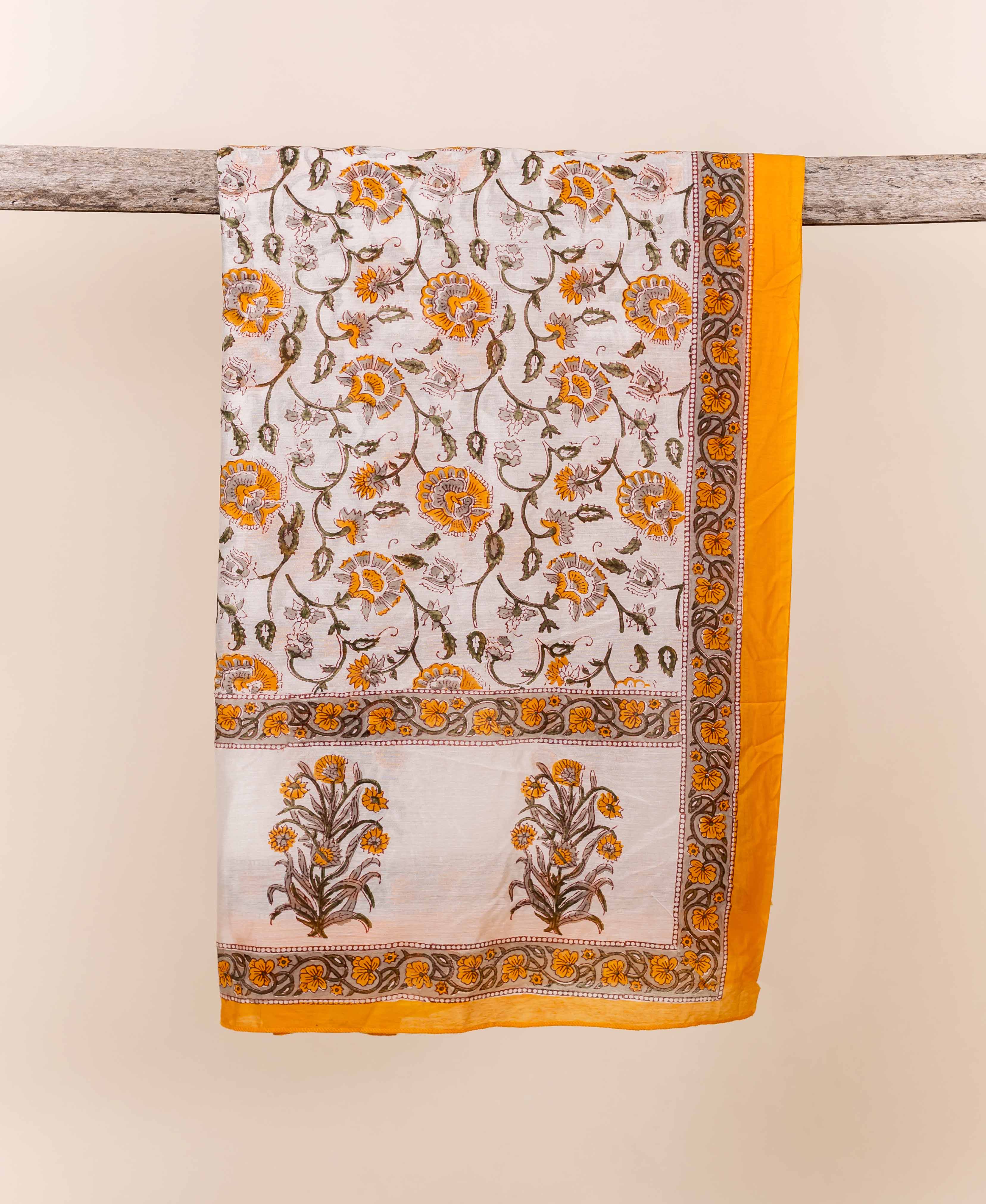 Yellow and white block printed floral chanderi dupatta draped over a rustic wooden branch.