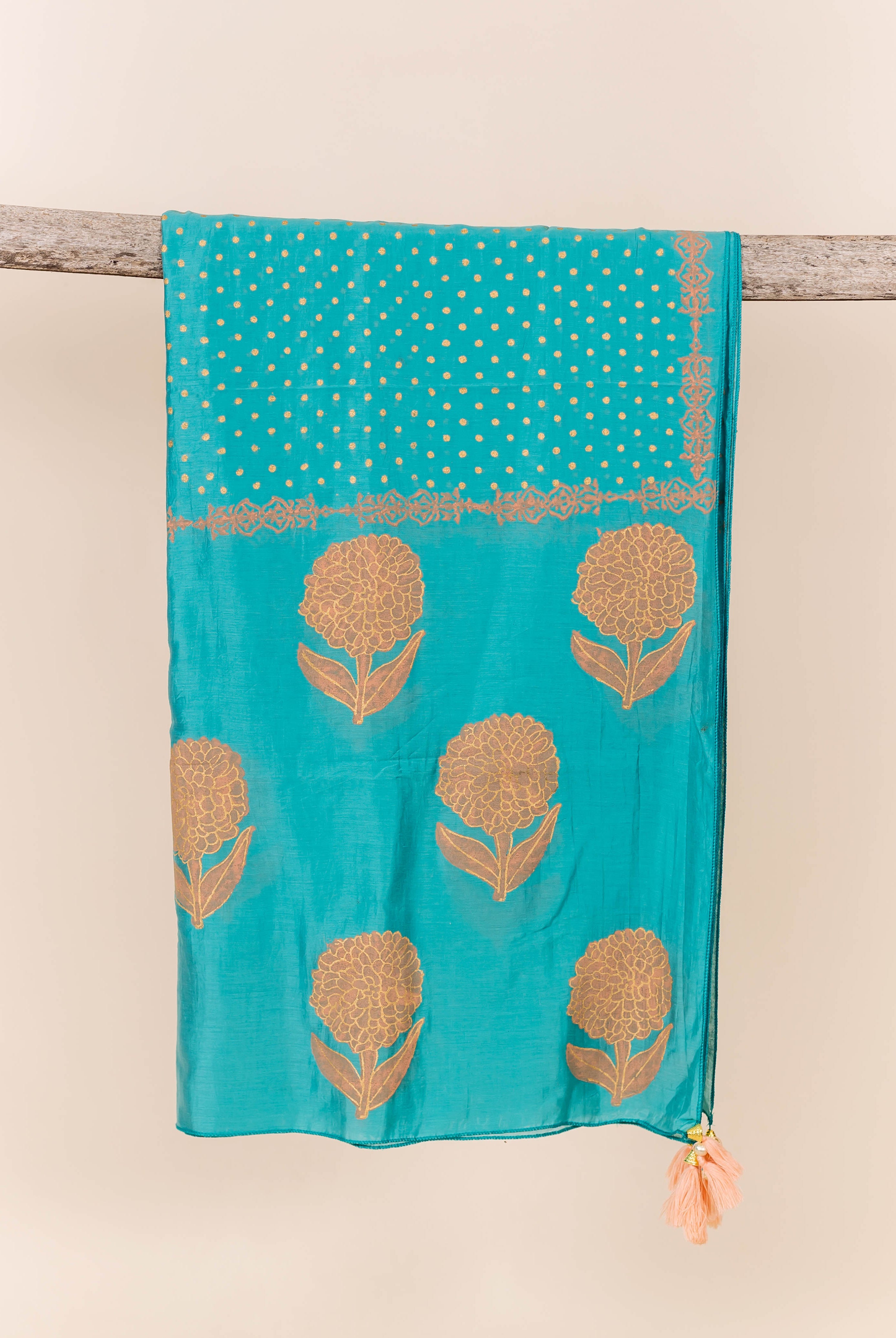Flat-lay turquoise dupatta with peach block print and tassel.