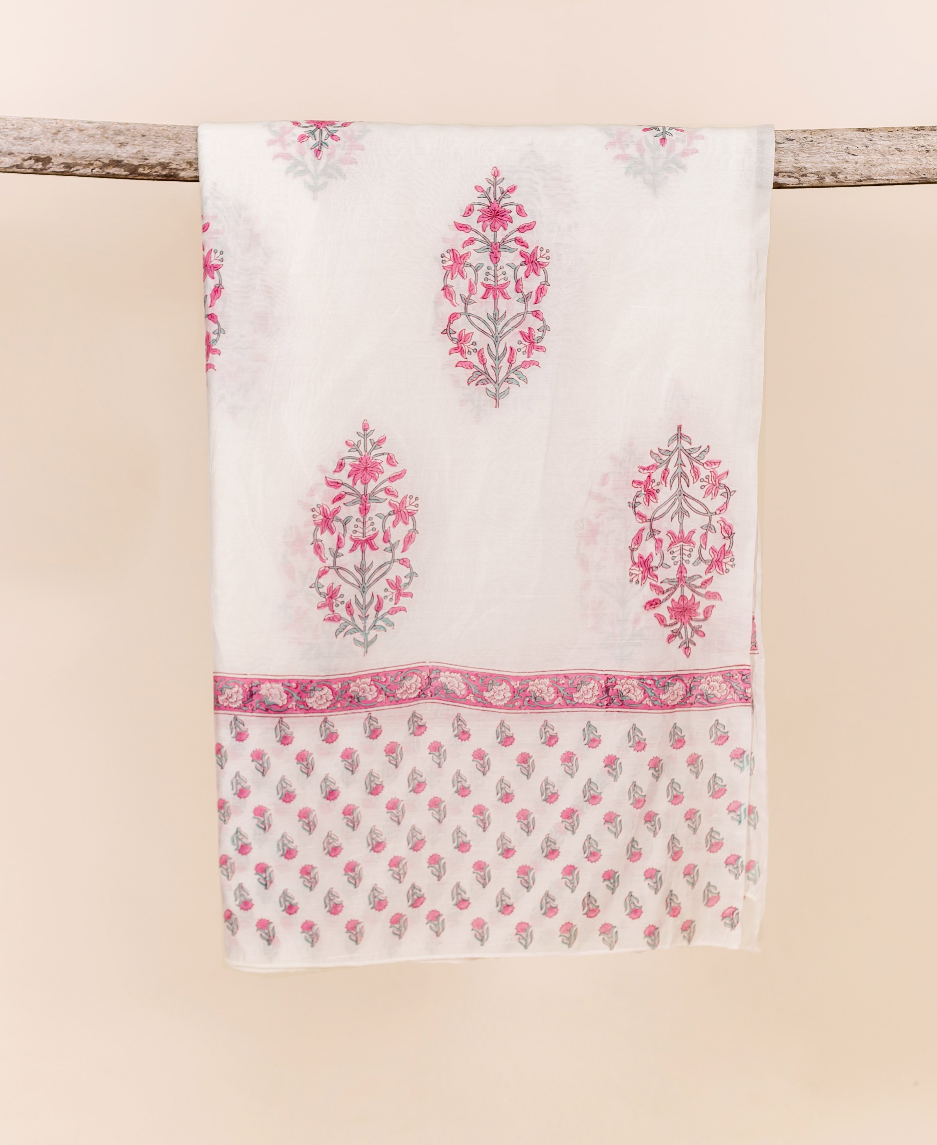 White hand-block printed dupatta with pink and grey floral motifs, draped on wood.