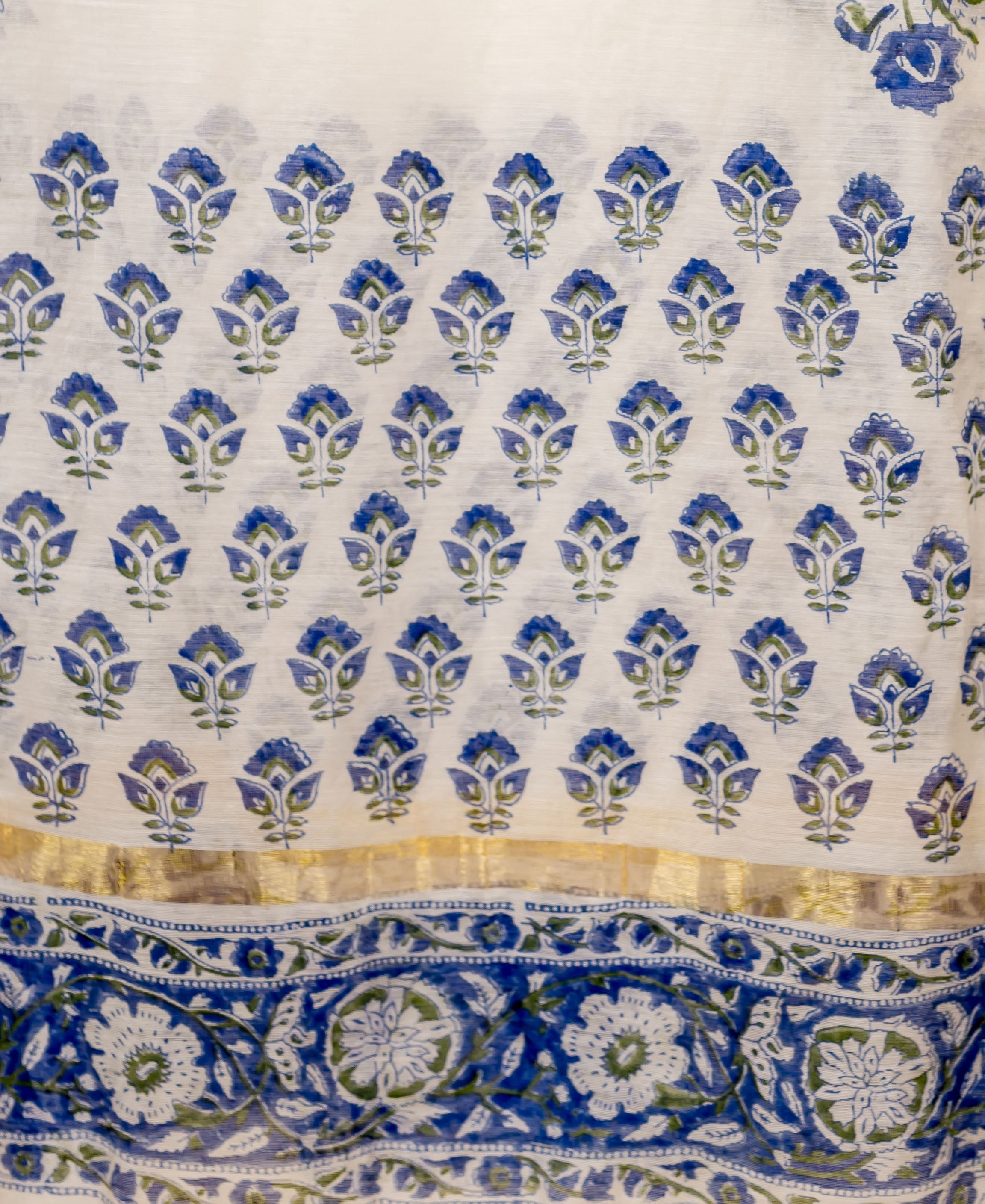 Close-up of a draped white Chanderi dupatta featuring blue floral block prints and a gold border.