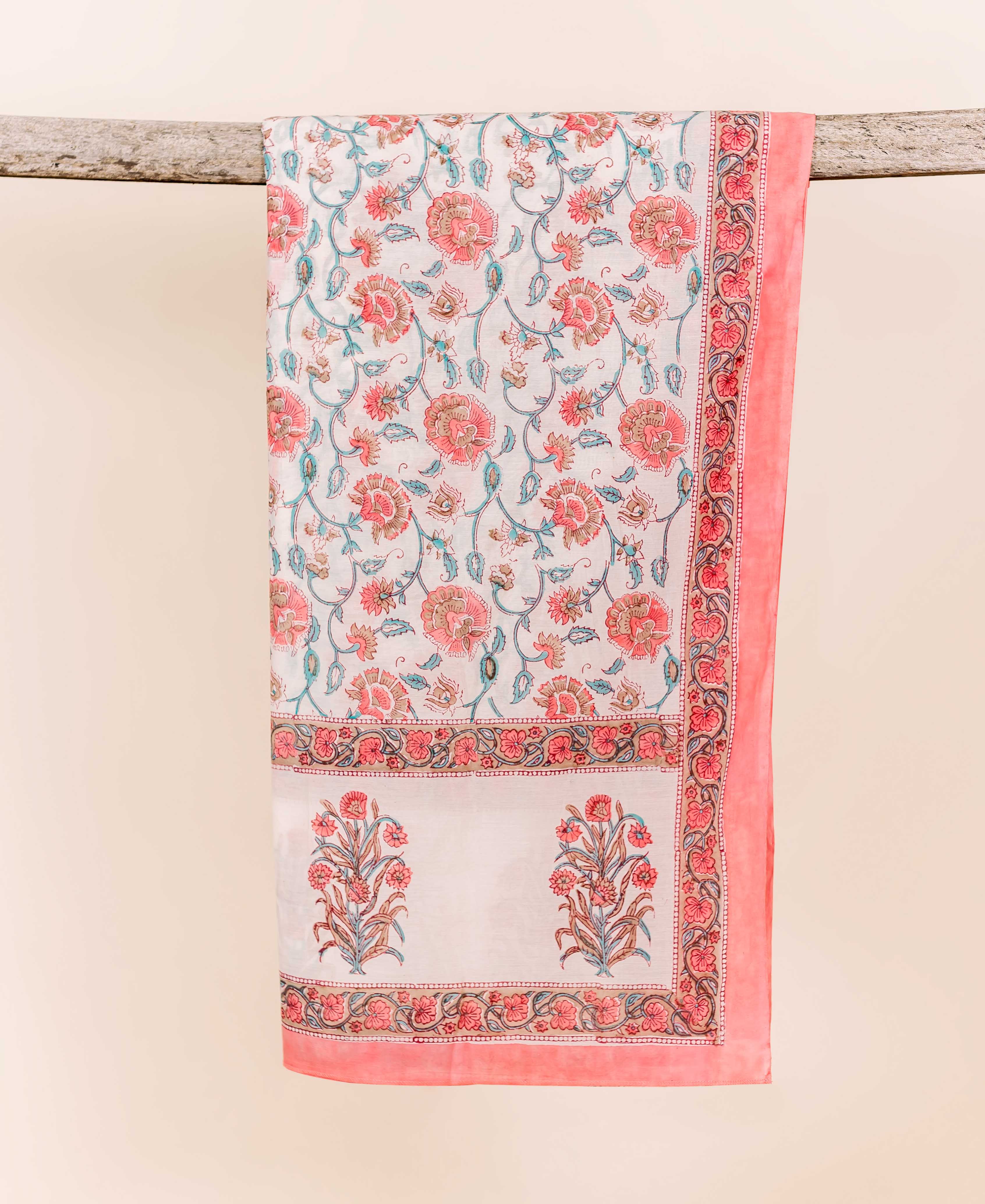 White and pink block printed dupatta with floral jaal pattern draped over a branch.