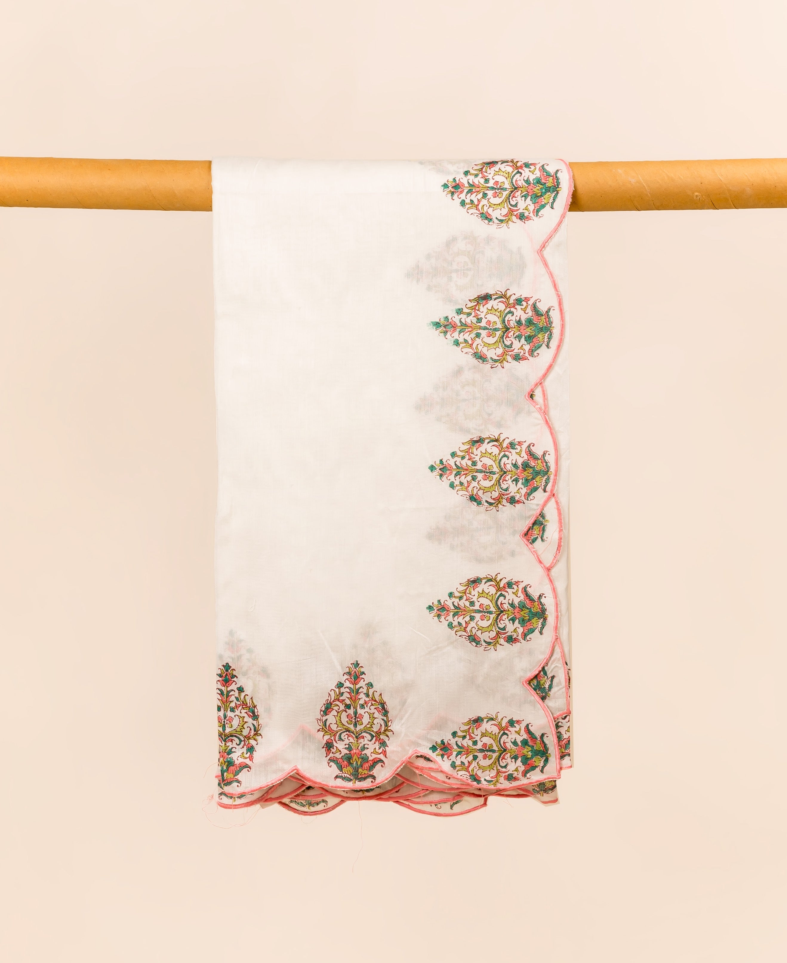 White hand block printed dupatta draped with colorful paisley motifs and pink scalloped edges.