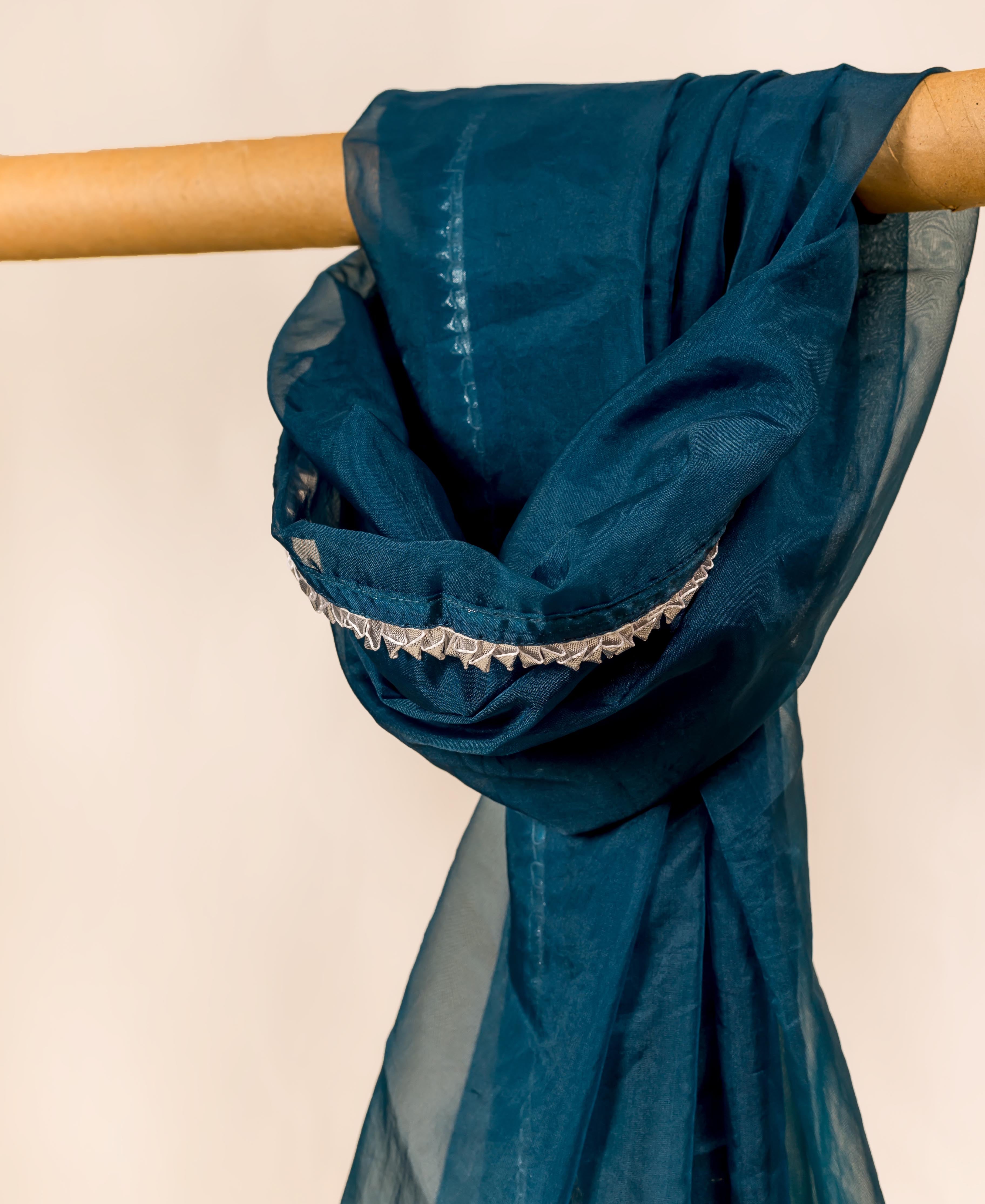 Teal blue organza dupatta with white trim, draped over a cylindrical object.