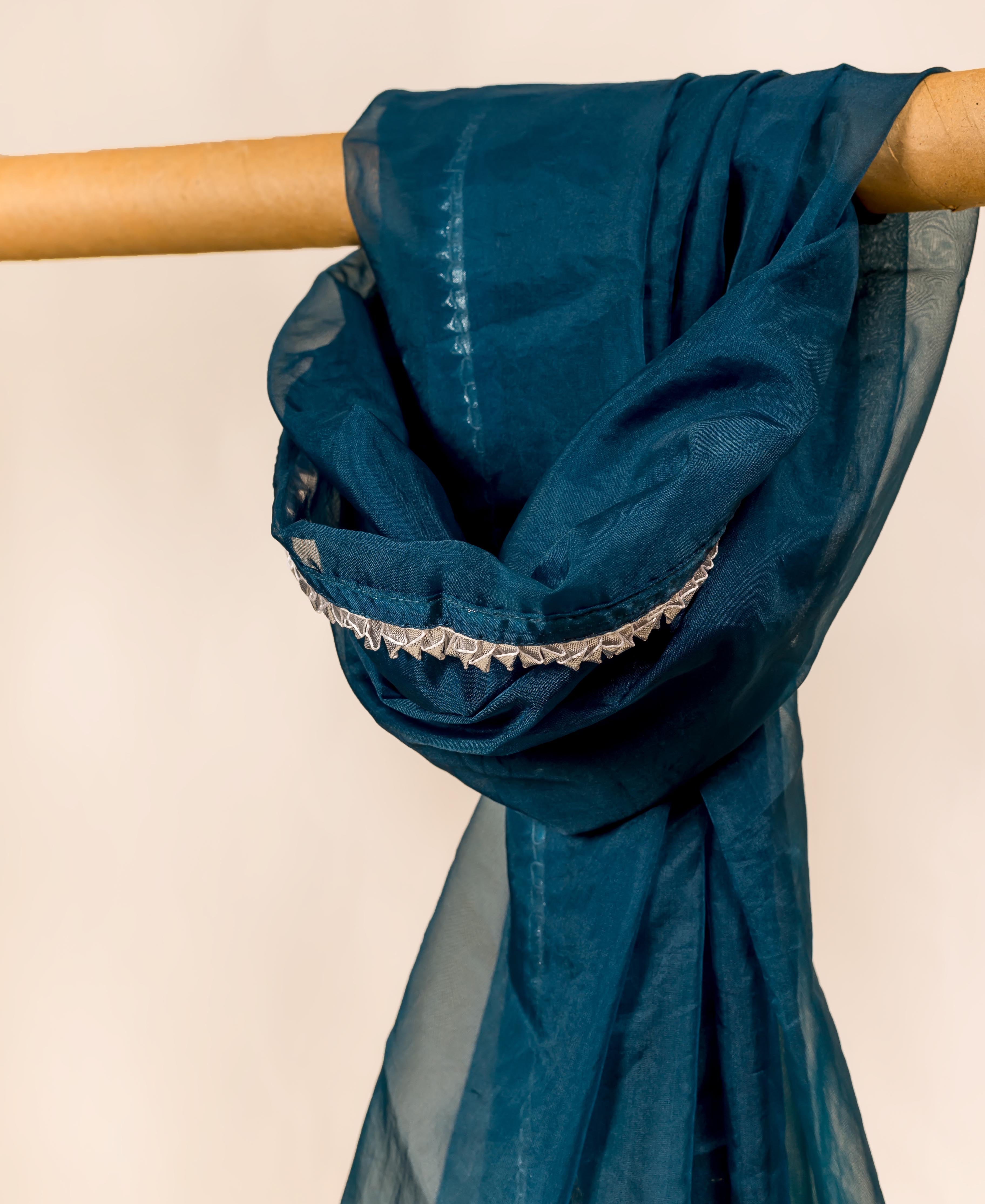 Teal blue organza dupatta with white trim, draped over a cylindrical object.