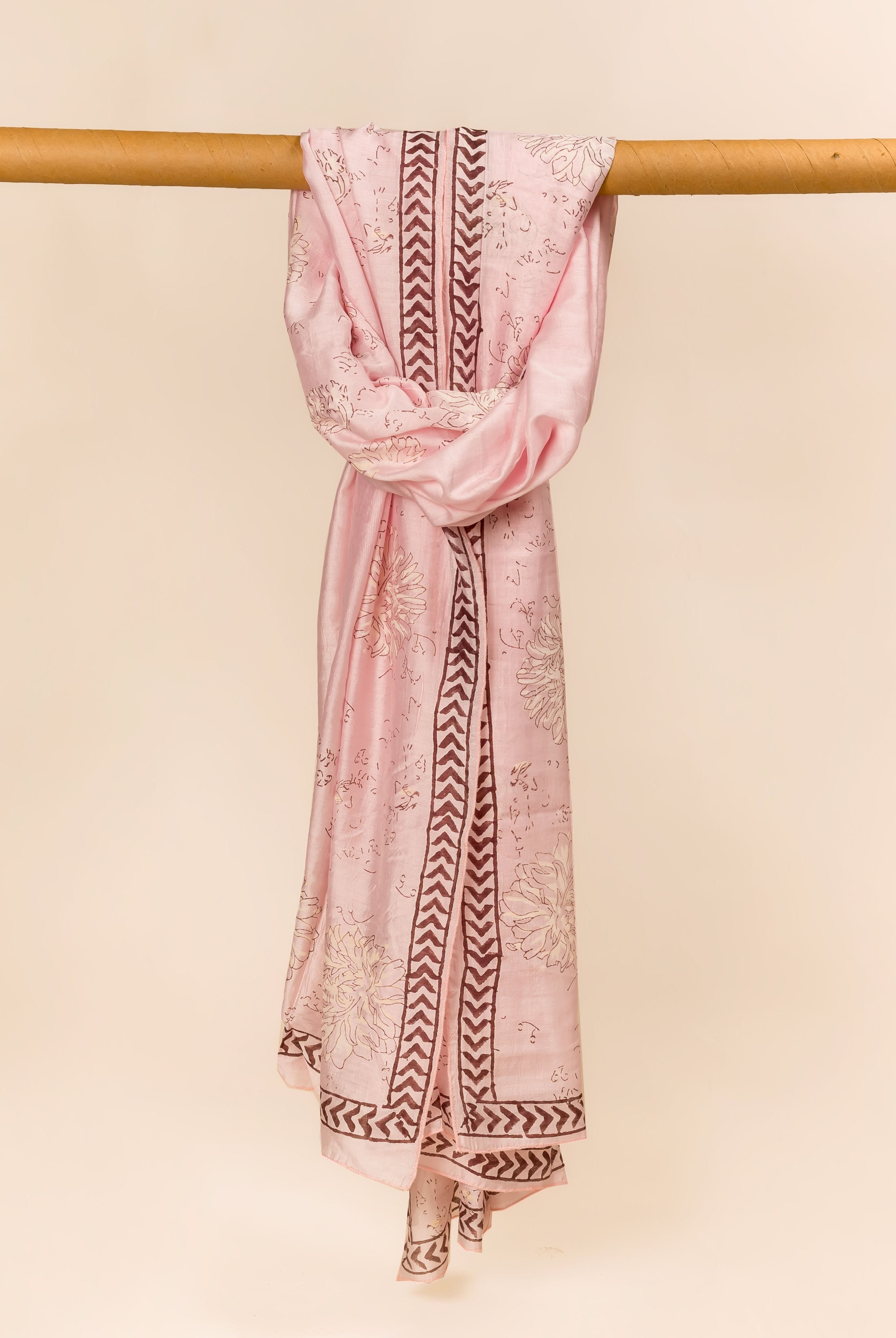 Blush pink hand block printed dupatta draped over a rod, with floral and brown chevron prints.