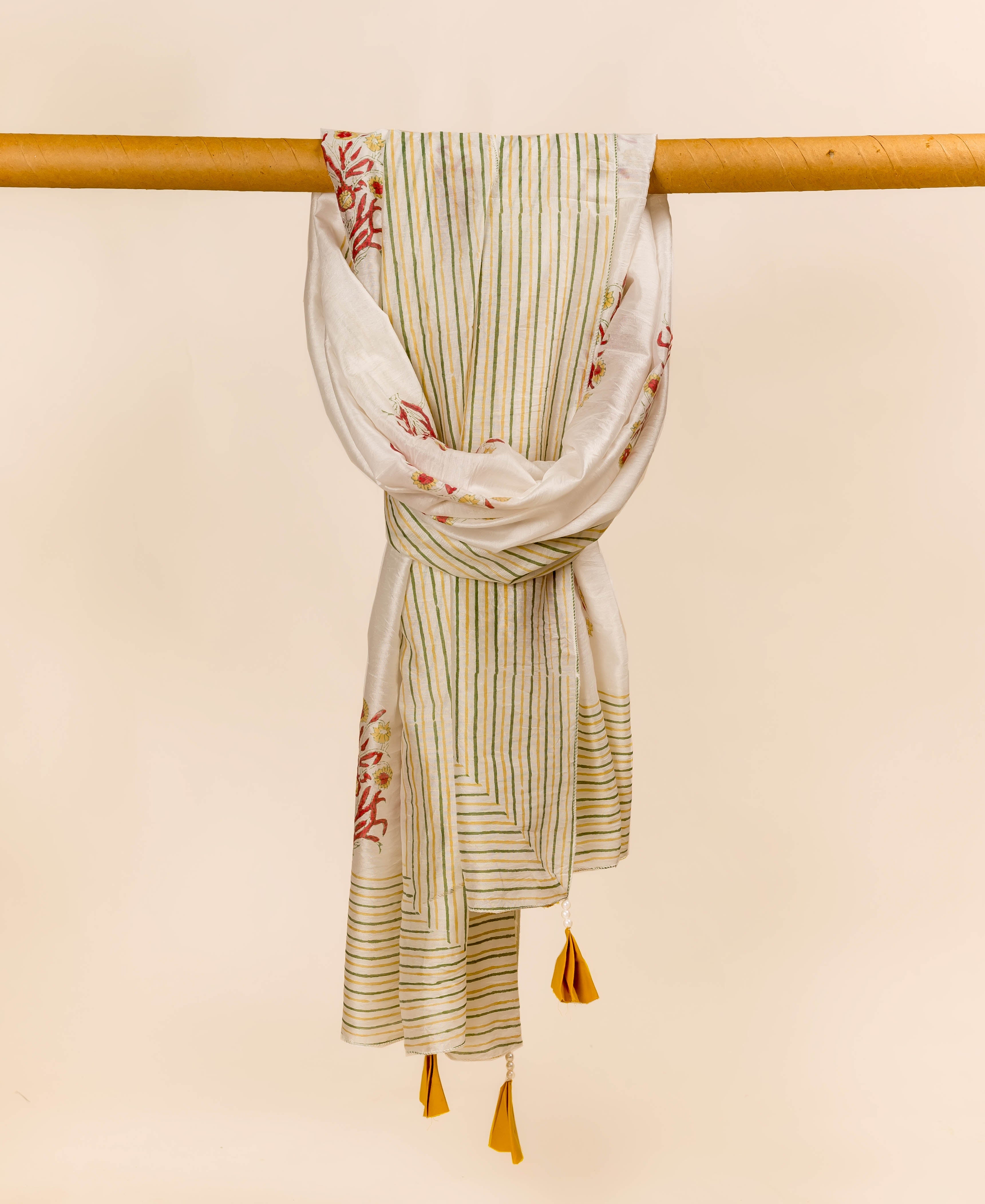 White hand-block printed dupatta with green-yellow vertical stripes and red floral motifs, draped on a bar.