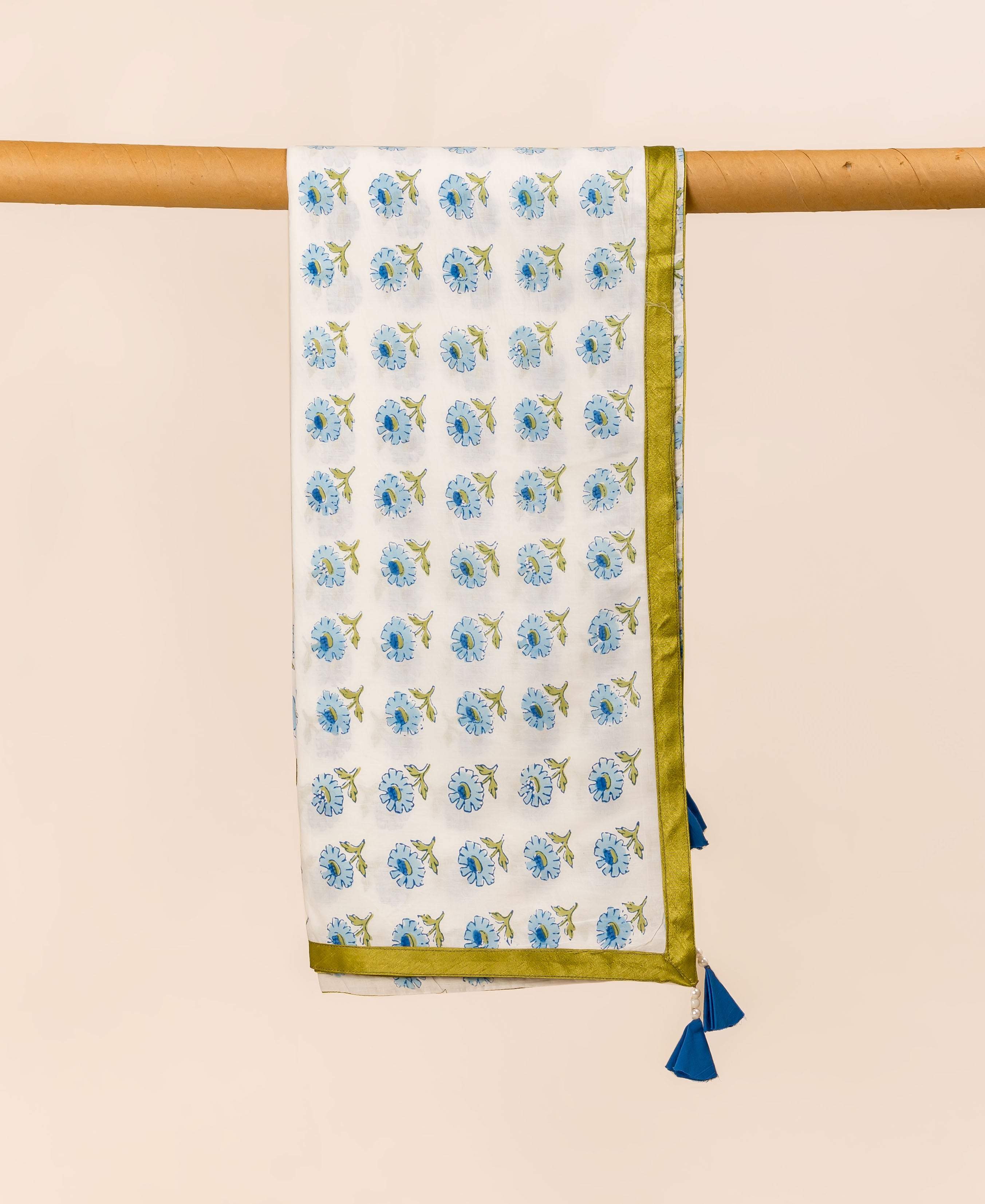 White and blue hand block printed dupatta with floral pattern, hanging on a wooden rod.