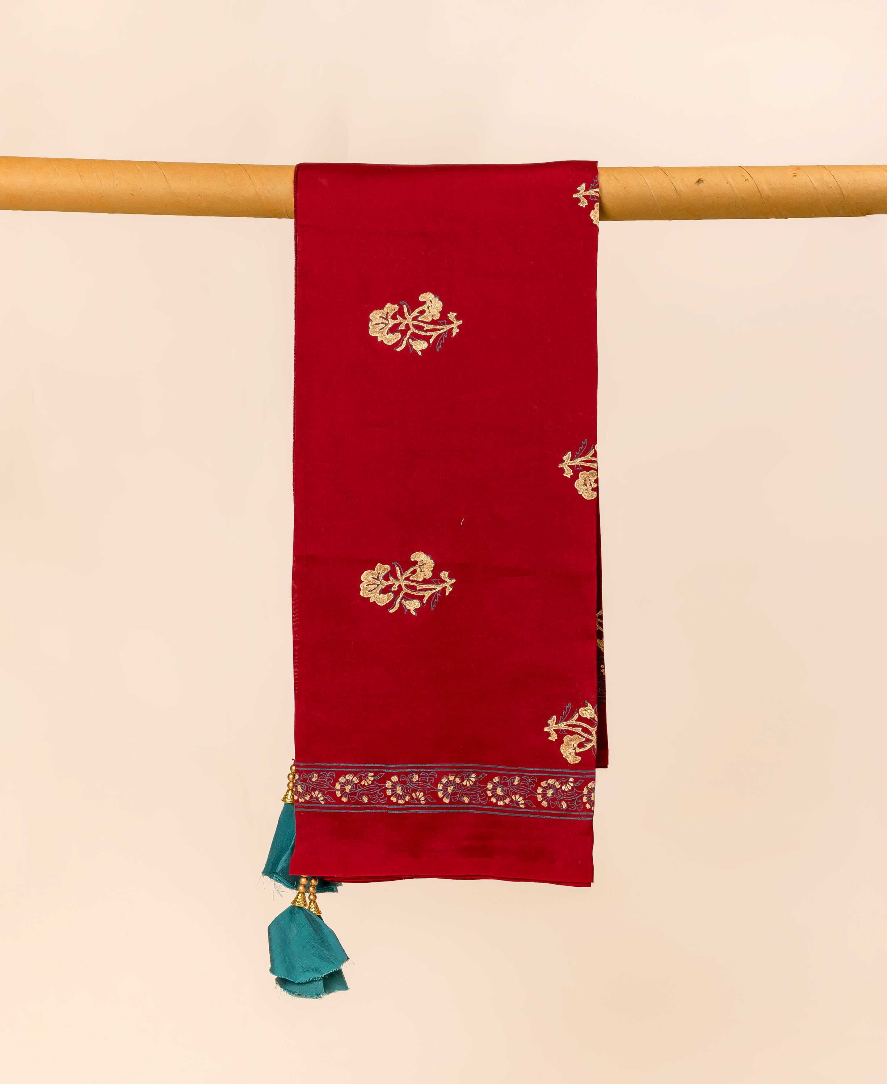 Maroon dupatta draped with gold floral block print and teal tassels.