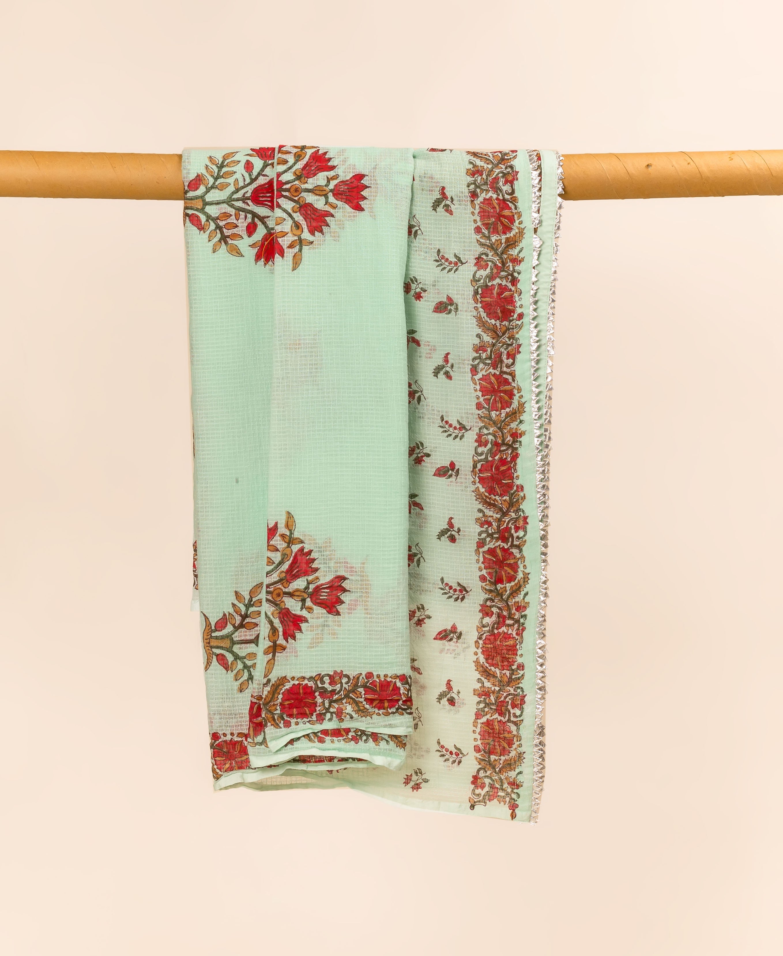Mint green hand block printed dupatta, featuring red floral patterns and a silver-edged border, hanging.