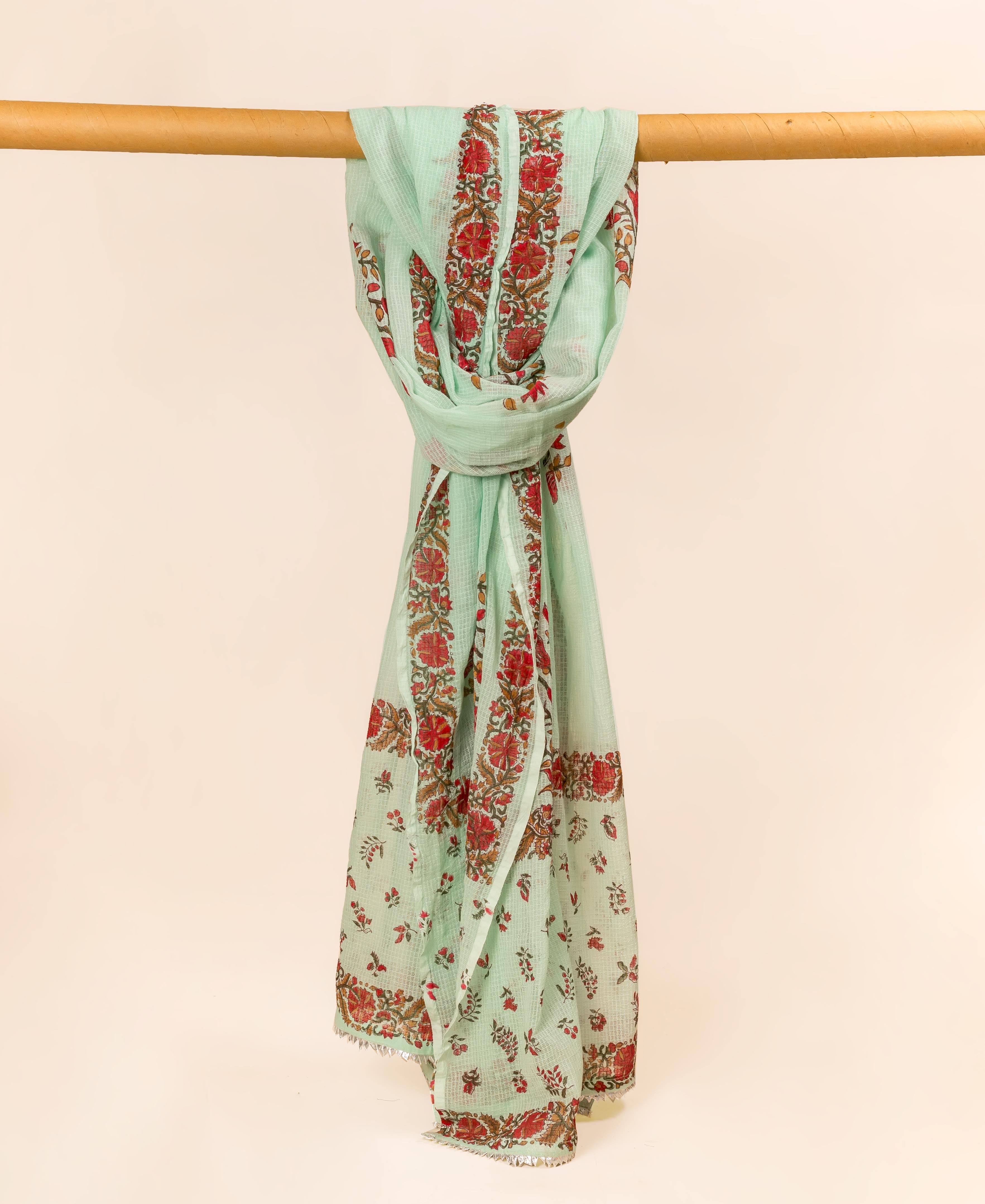 Mint green hand block printed dupatta with red floral patterns, gracefully draped on a wooden bar.