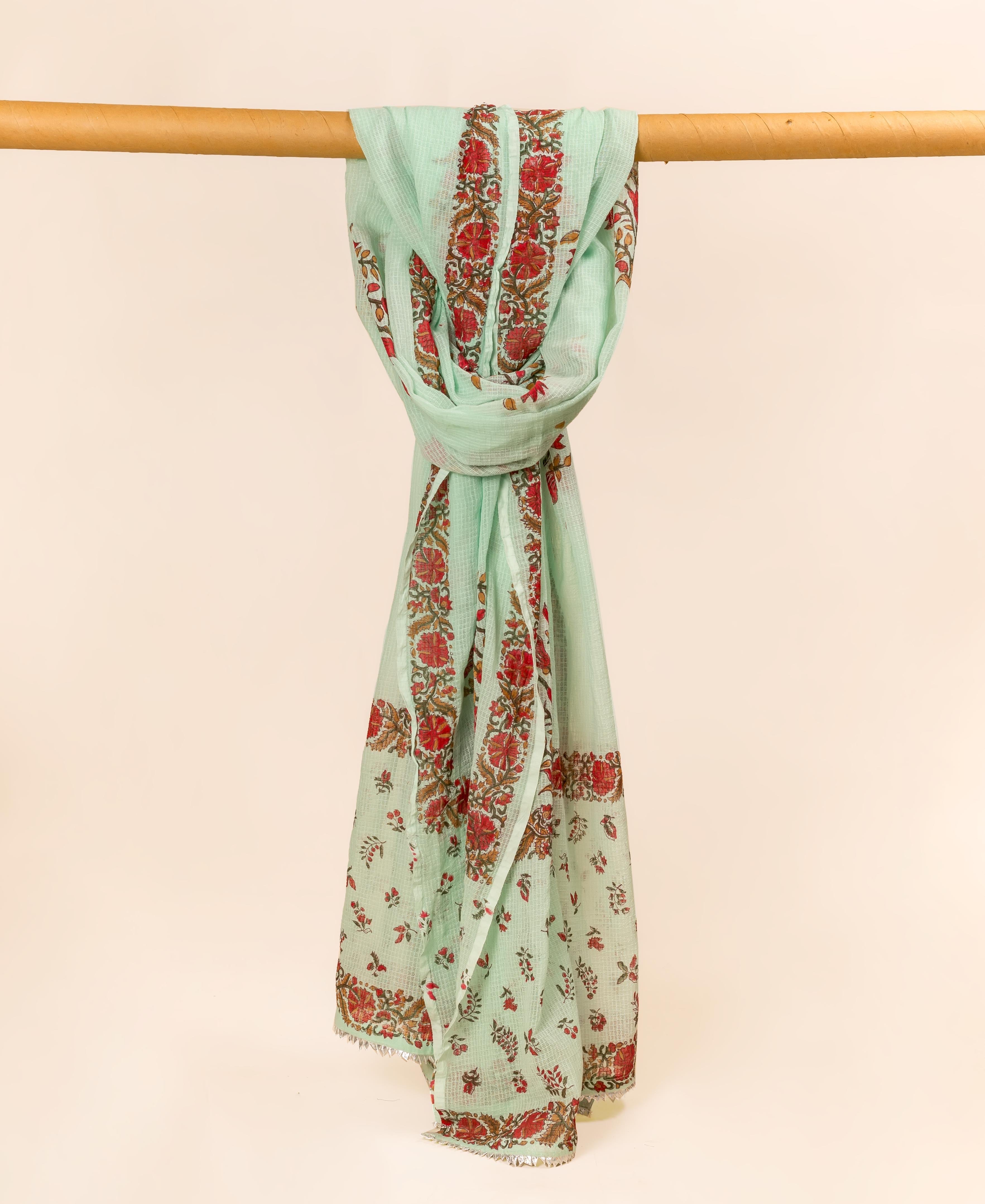 Mint green hand block printed dupatta with red floral patterns, gracefully draped on a wooden bar.