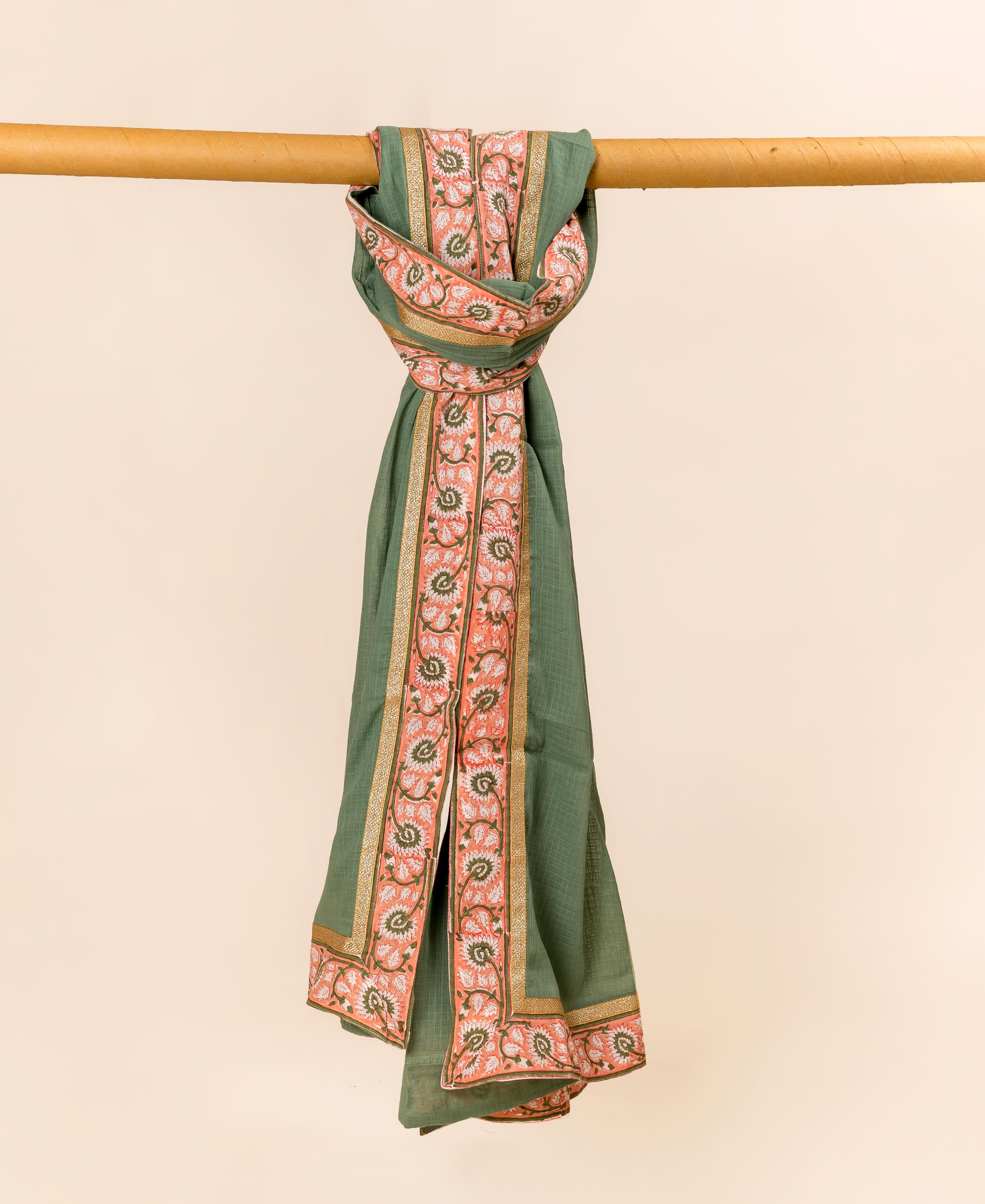 Green Kota Doria dupatta with block-printed coral floral border, hanging loosely from a wooden rod.