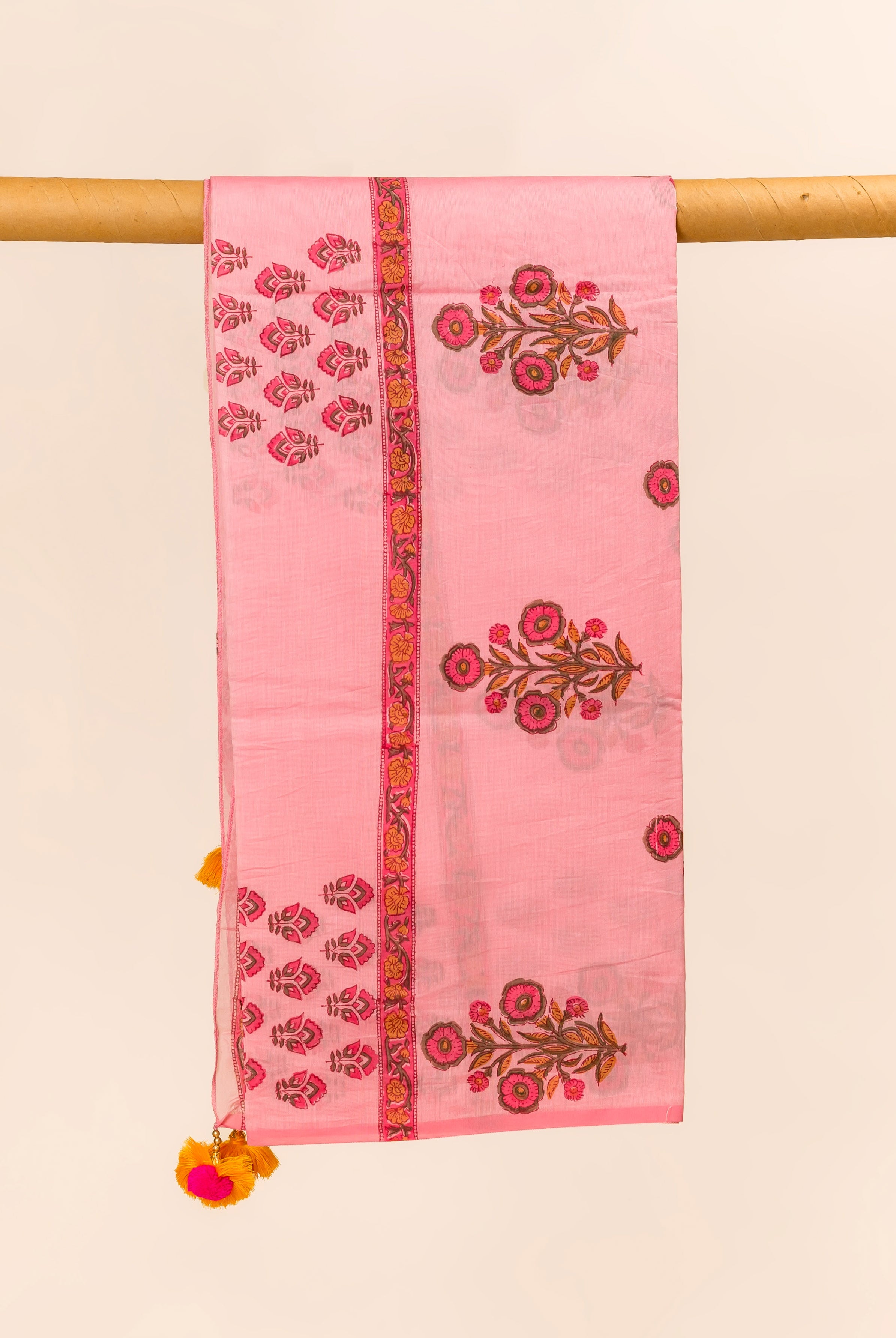 Pink hand block printed Chanderi dupatta with floral design and tassels, hanging.