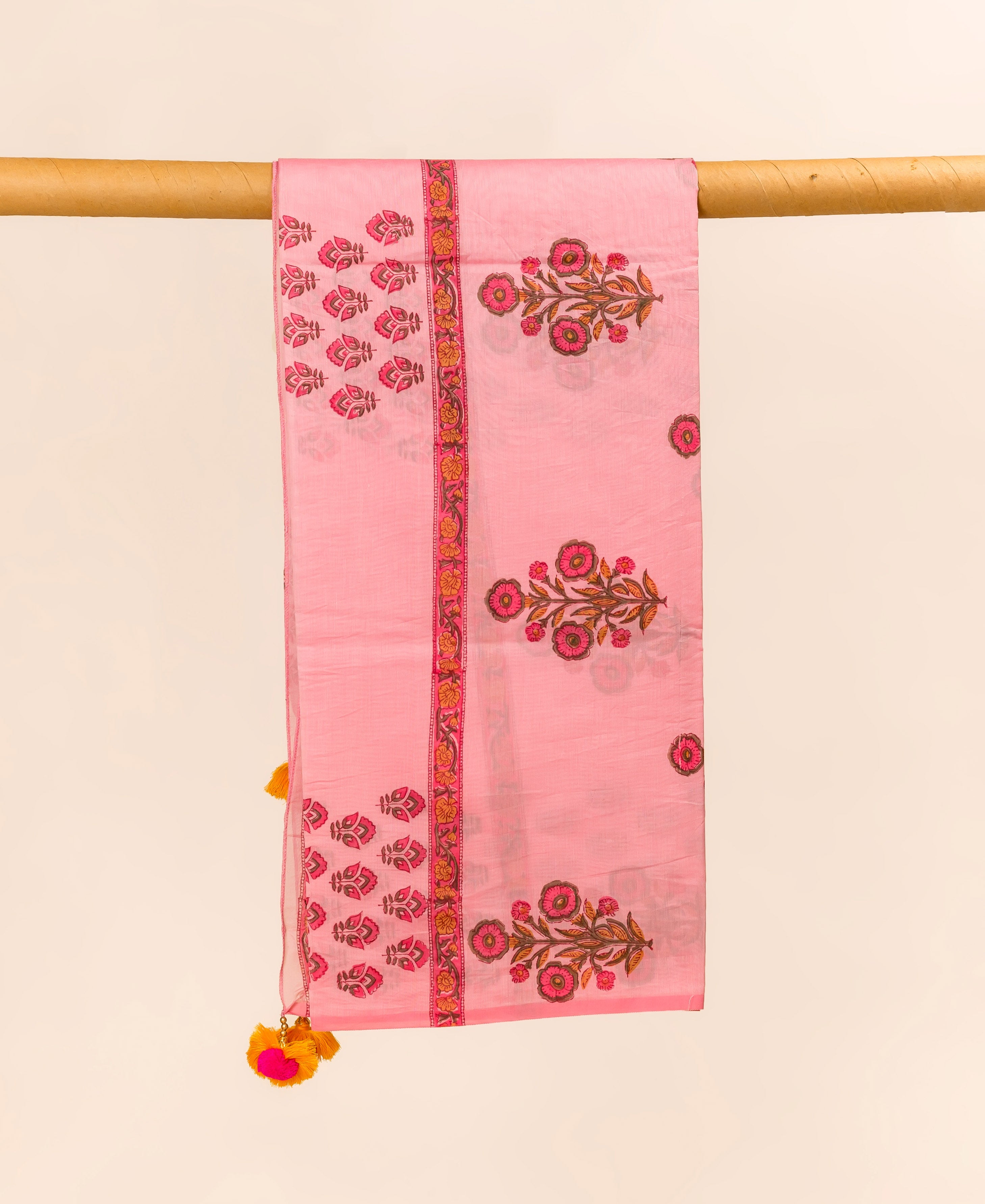 Pink hand block printed Chanderi dupatta with floral design and tassels, hanging.