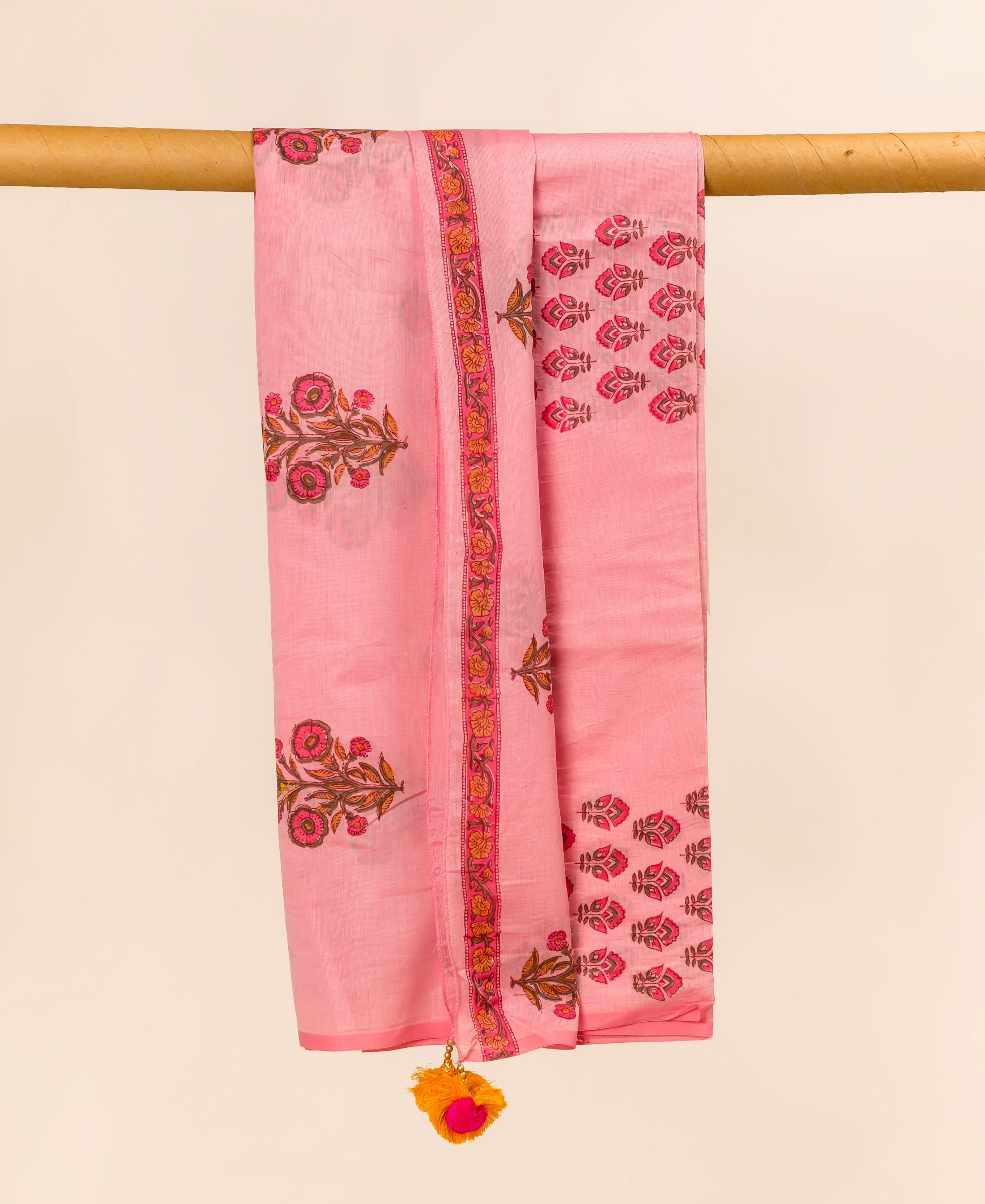 Pink Chanderi dupatta with hand block print, hanging from a wooden rod.