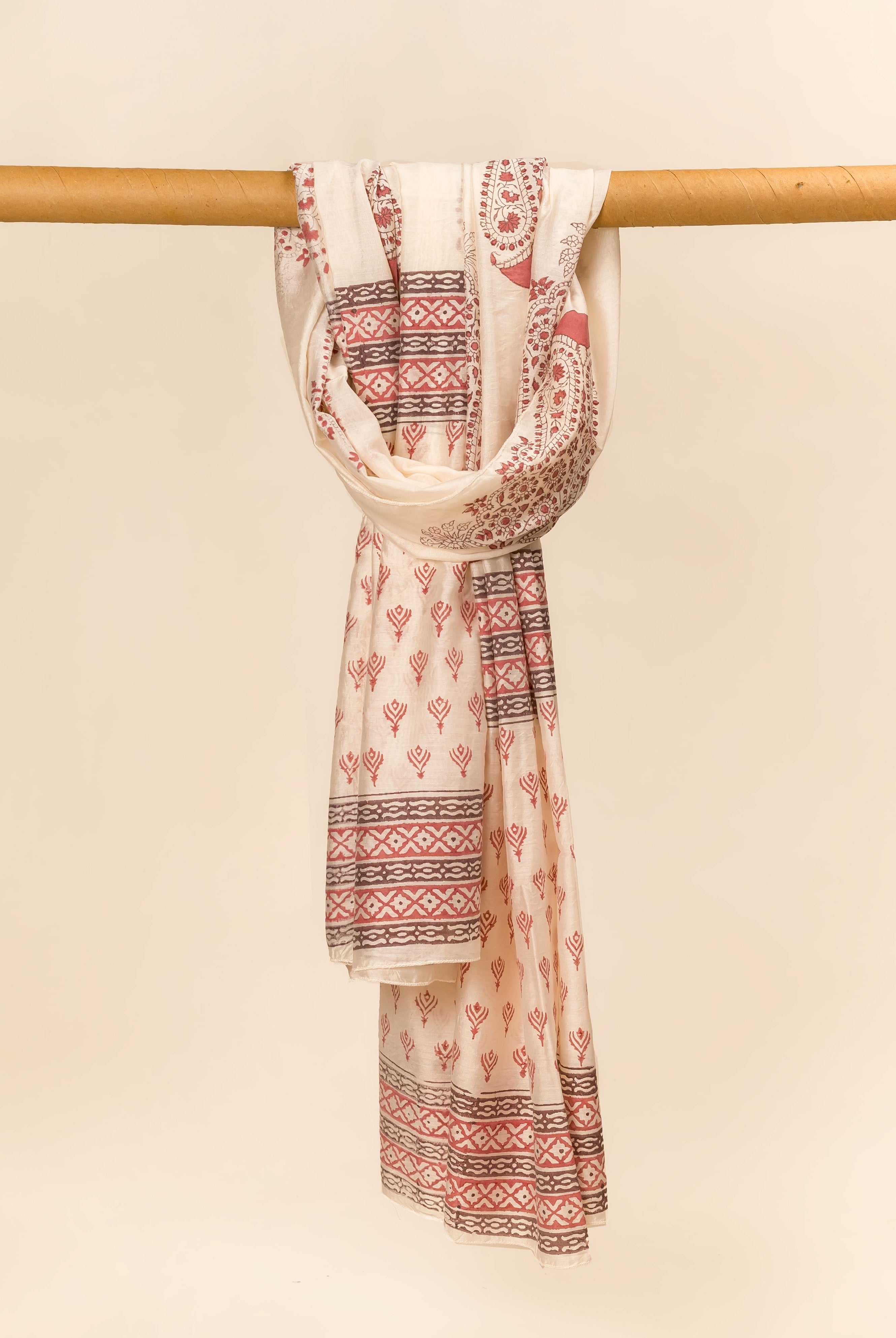 Off-white hand block printed dupatta with red geometric and paisley patterns draped on a rod.