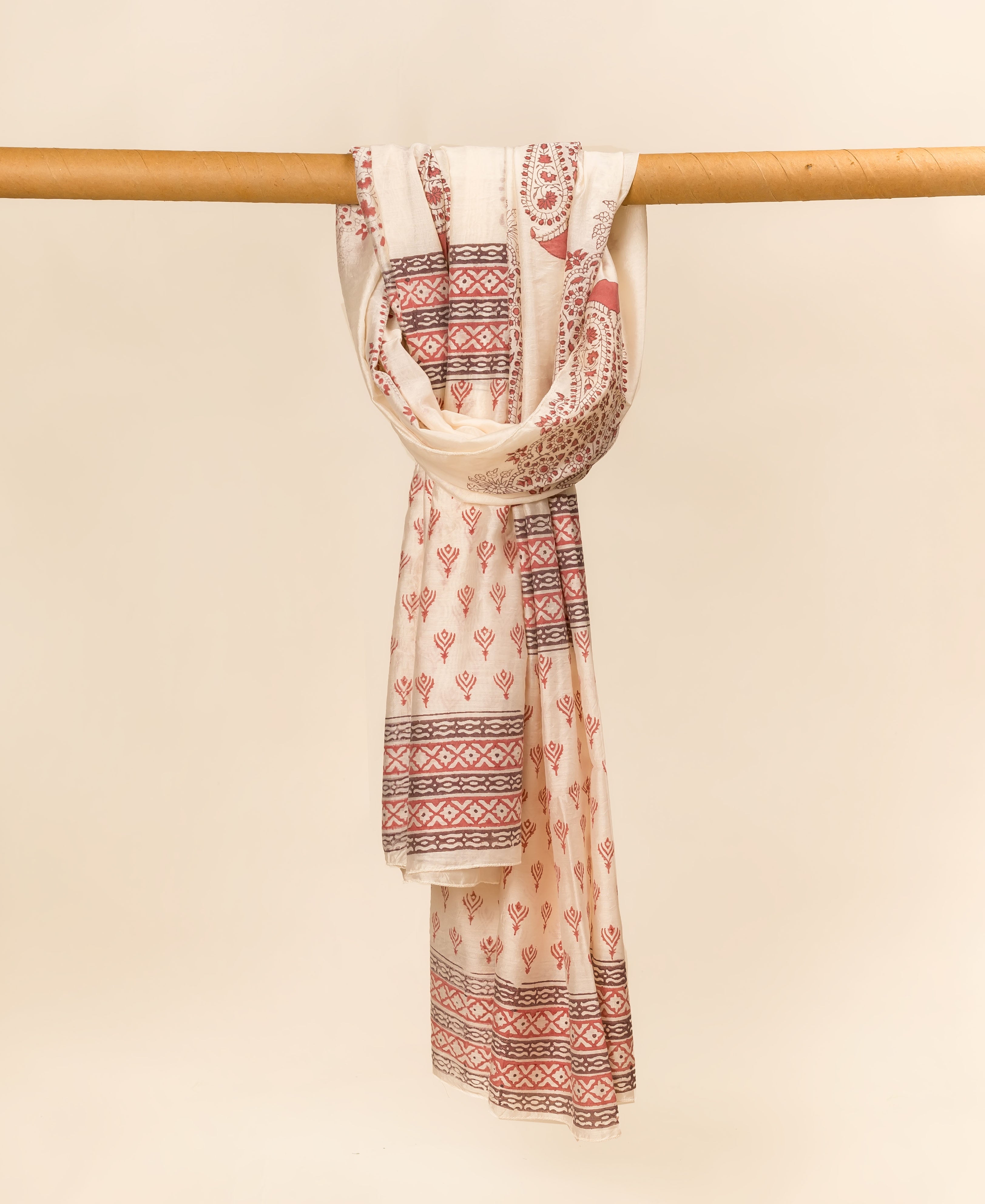 Off-white hand block printed dupatta with red geometric and paisley patterns draped on a rod.