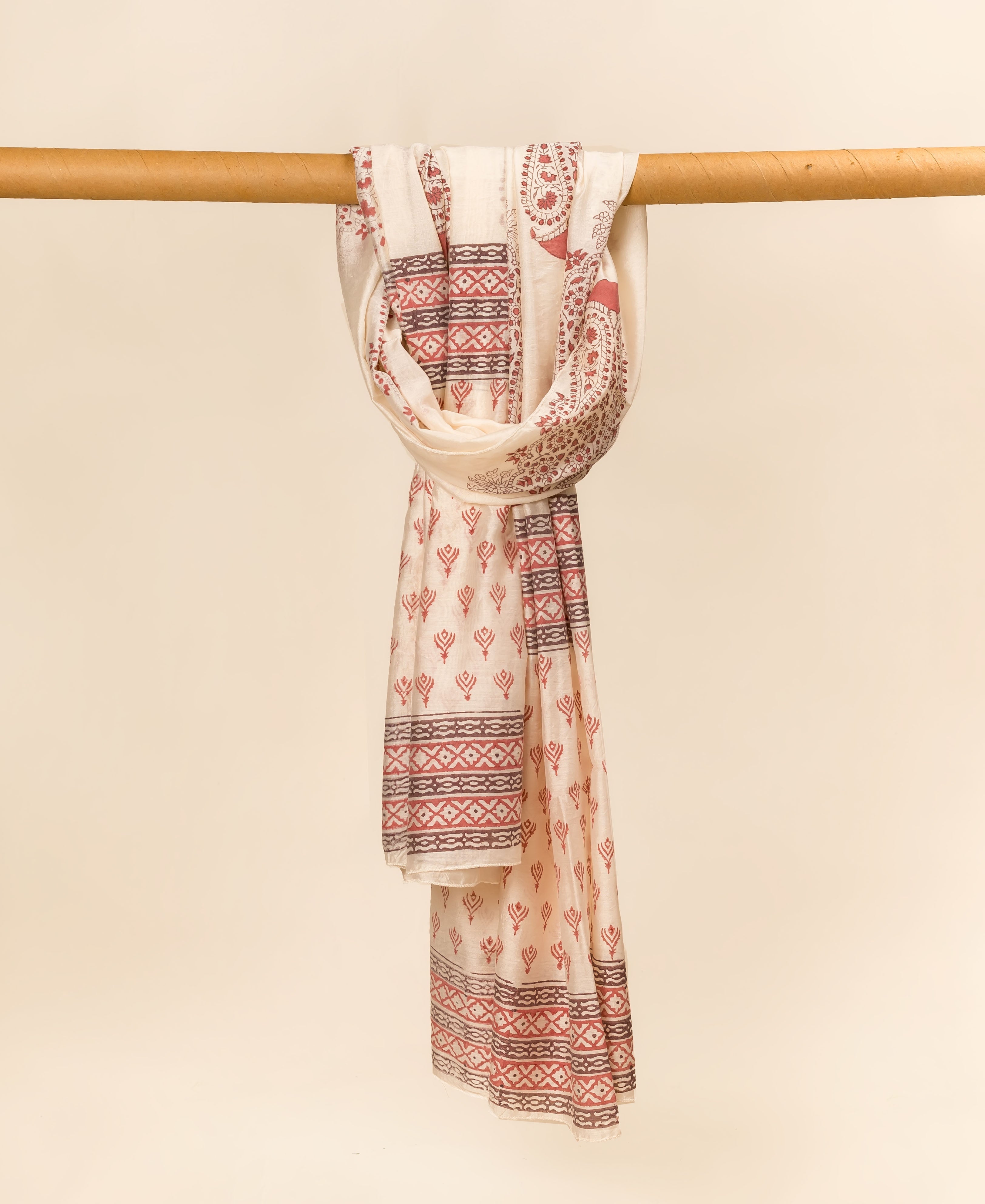 Off-white hand block printed dupatta with red geometric and paisley patterns draped on a rod.