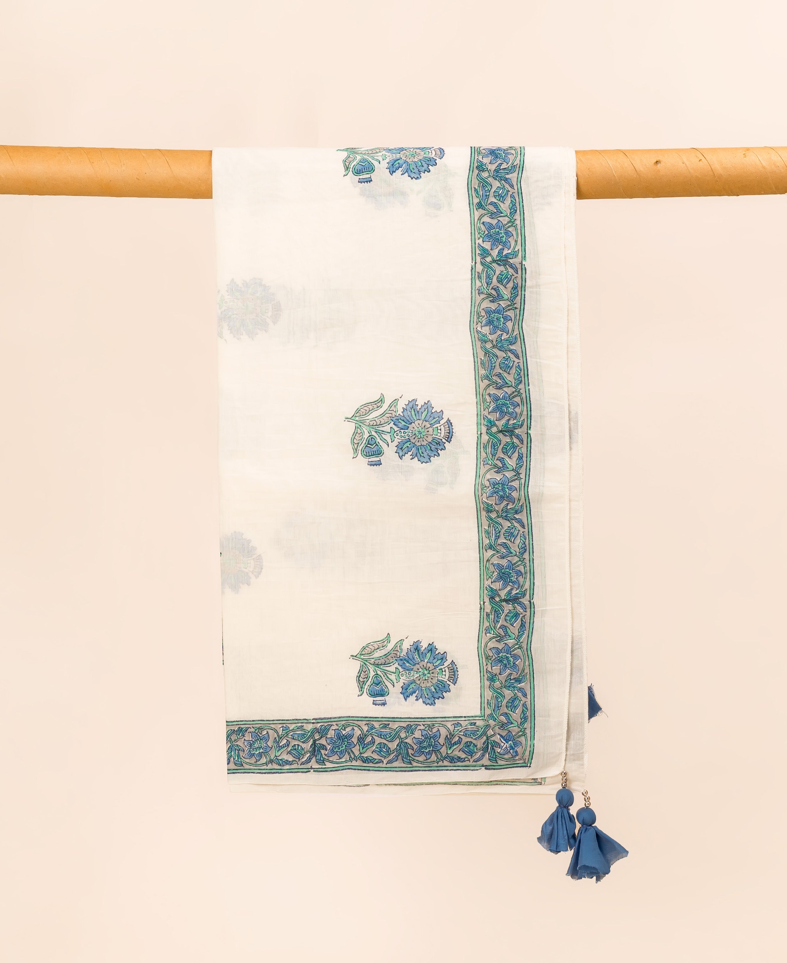 White and blue hand block printed dupatta with floral pattern, hanging from a wooden rod.