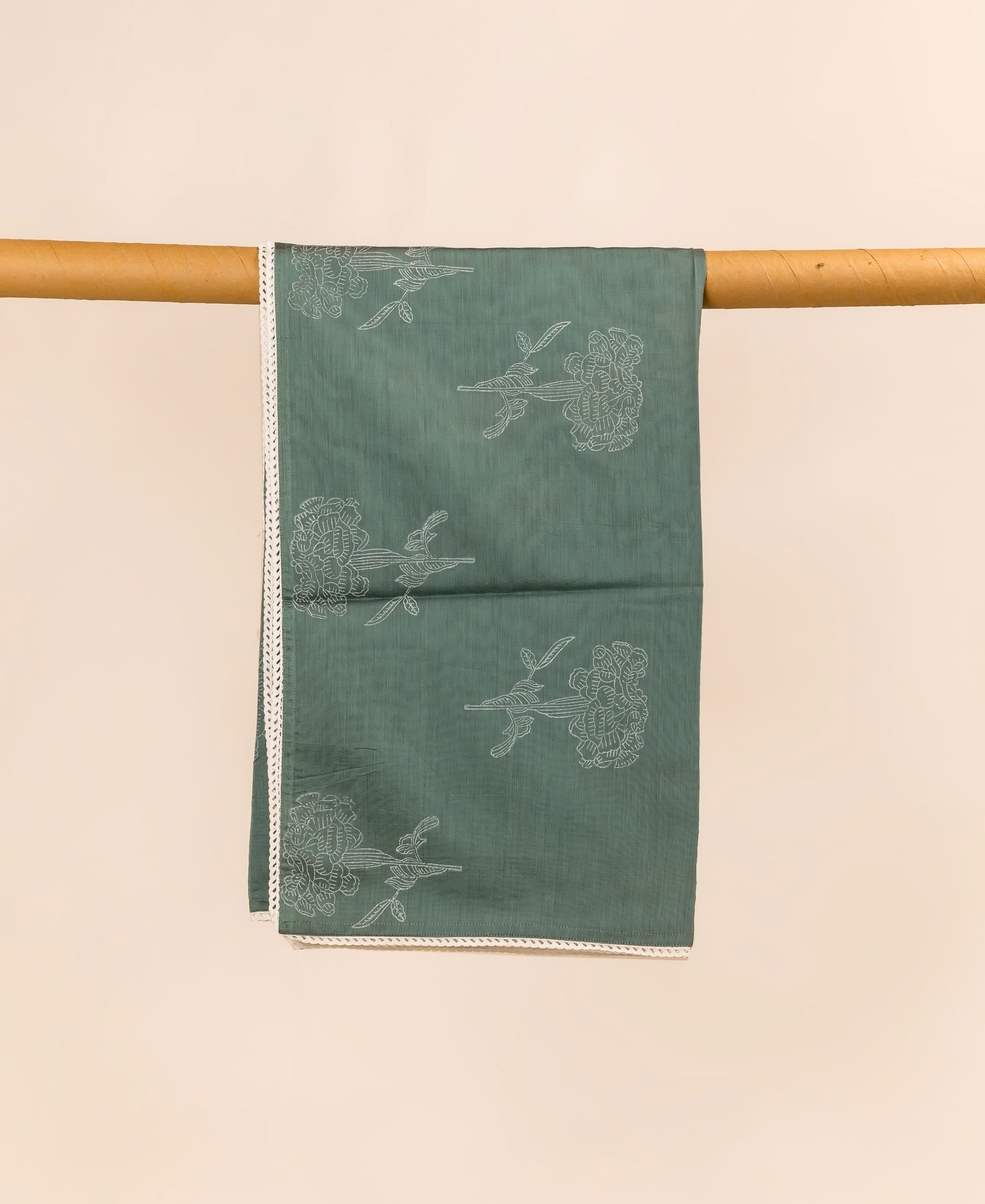Green dupatta with white floral print and lace trim, folded on a wooden dowel.