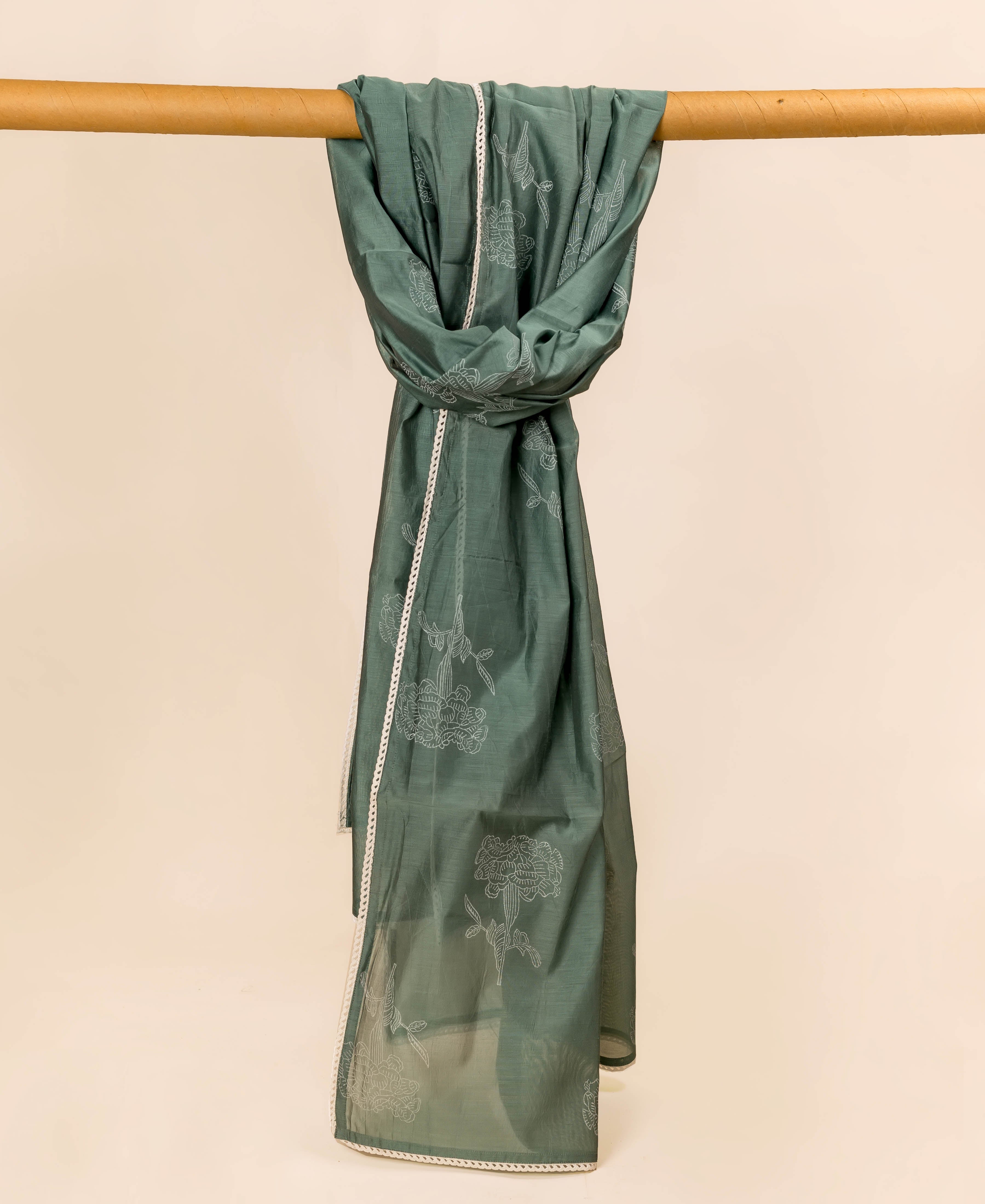 Green hand-block printed dupatta with white floral patterns and lace trim draped over a bar.