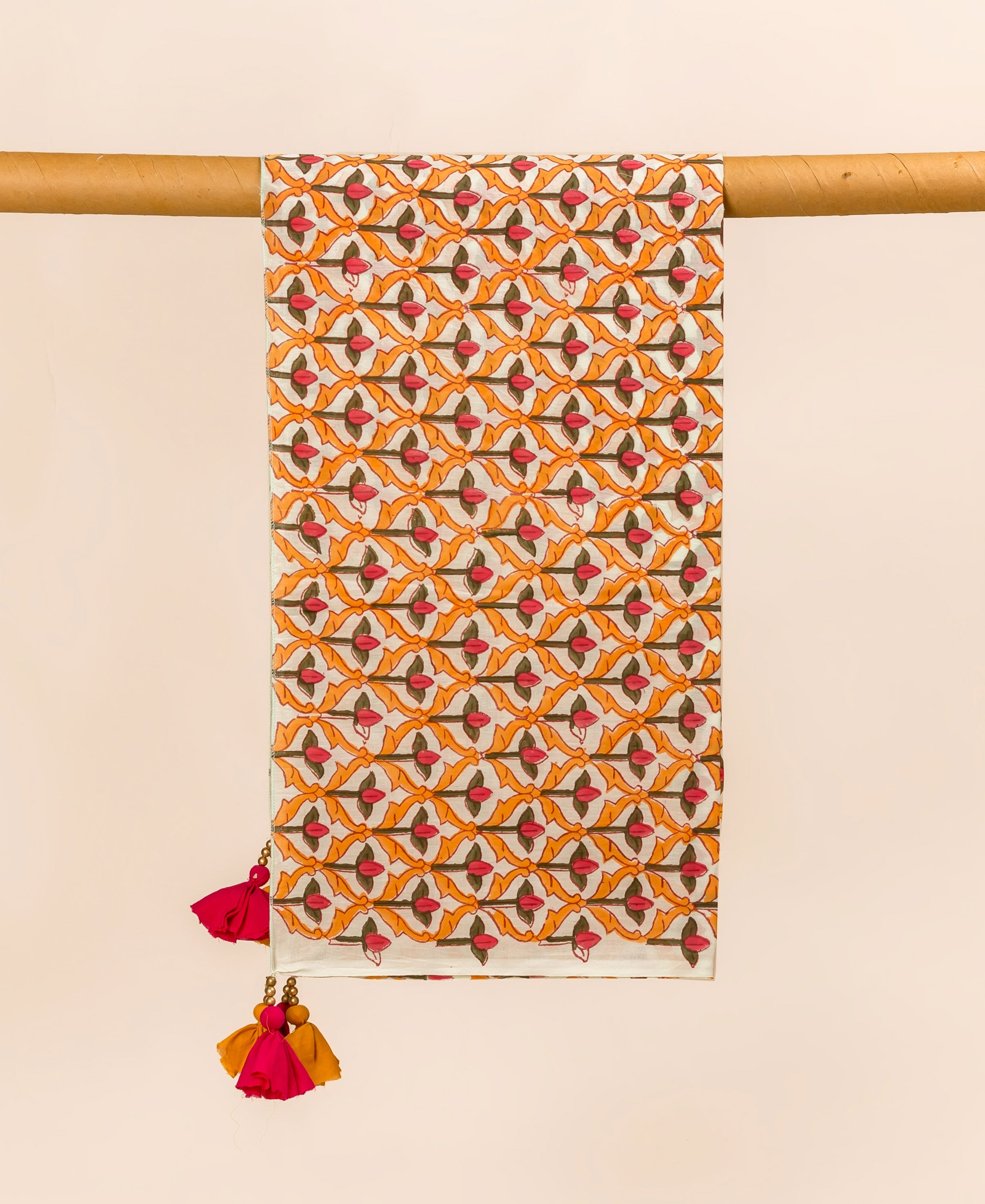 Vibrant orange, pink, and brown patterned dupatta with tassels on a wooden dowel.