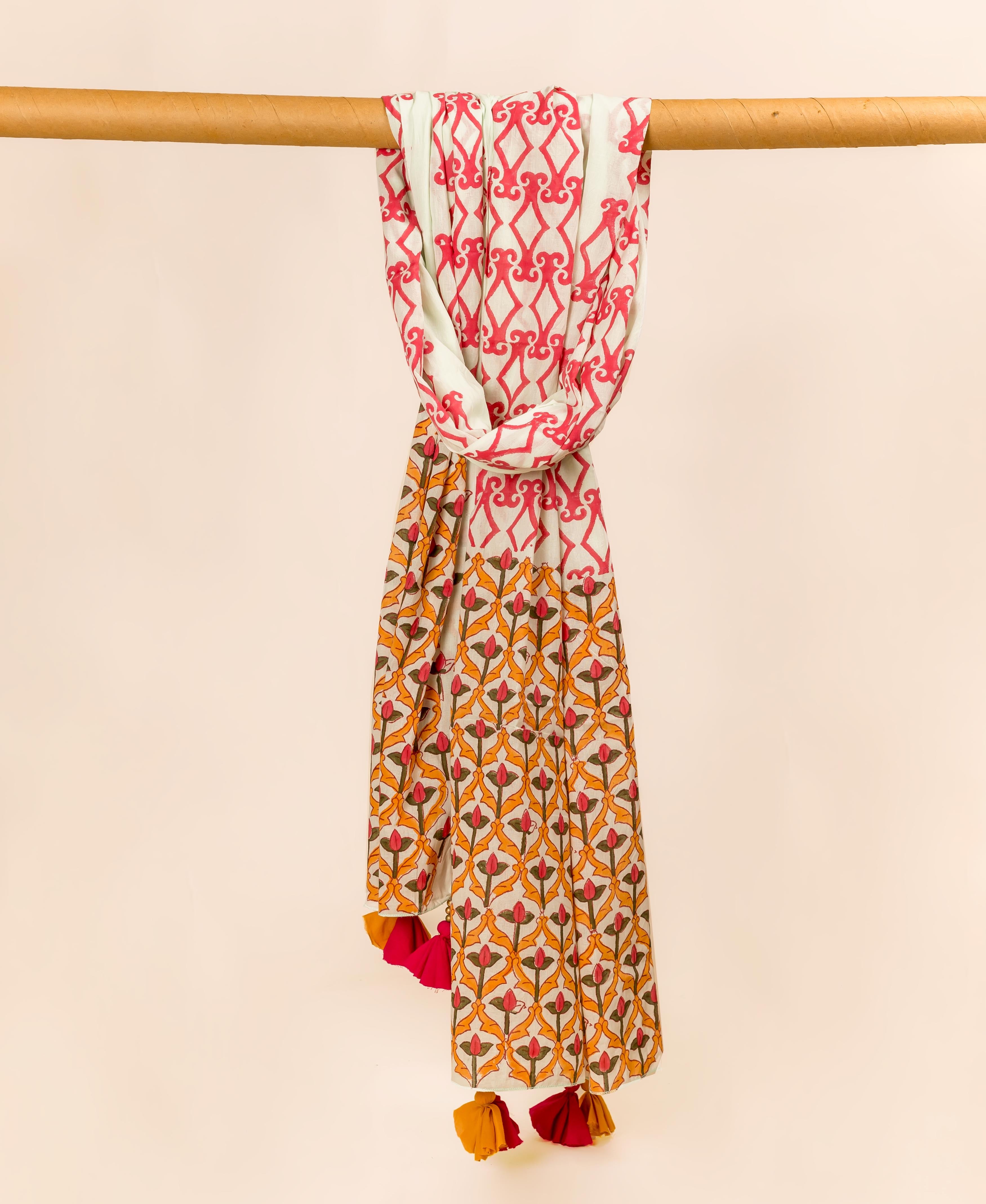 Hand block printed cotton dupatta with red geometric and orange floral patterns, hanging with tassels.