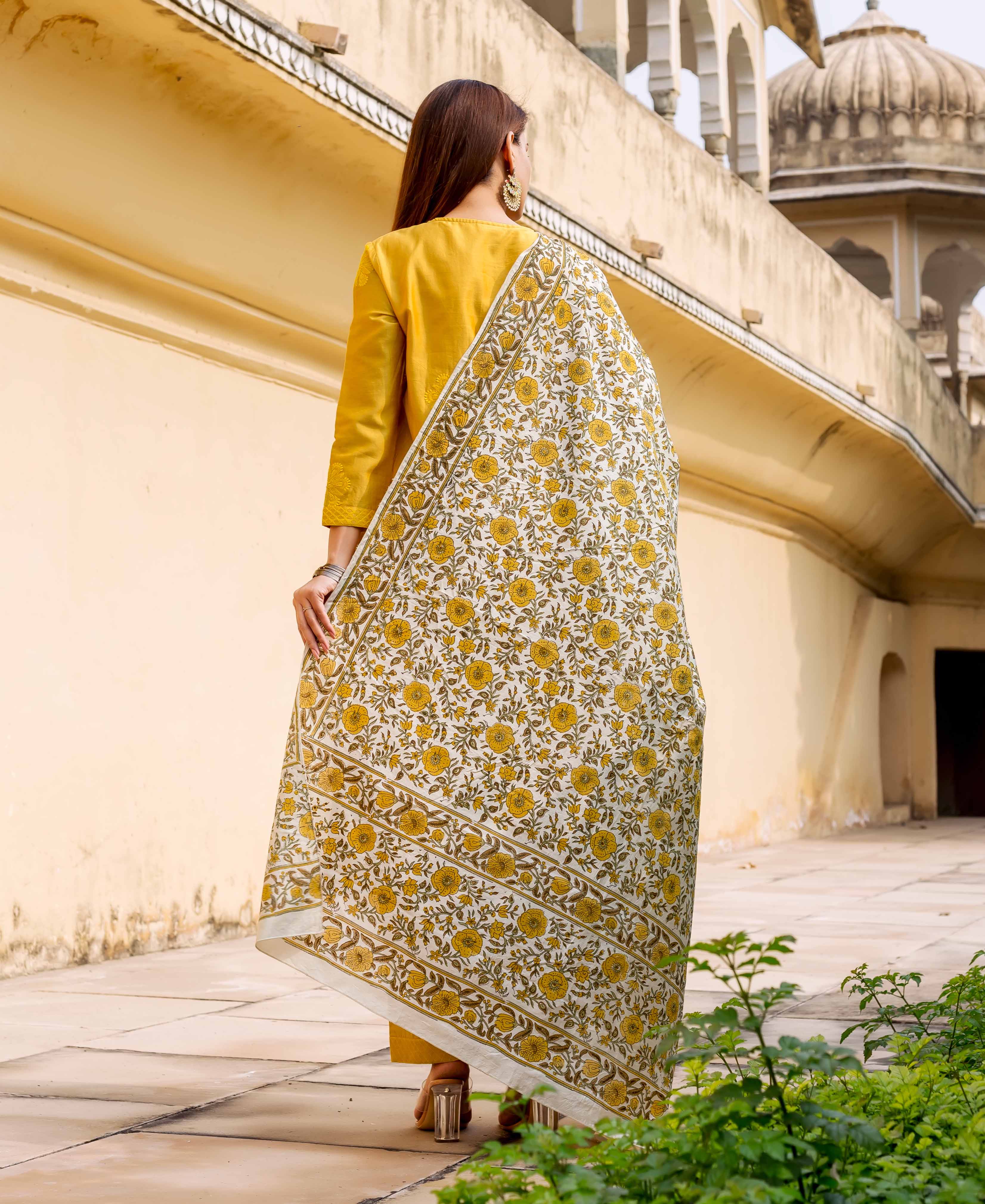 Model from back wearing a white and yellow hand block printed dupatta over a mustard kurta.