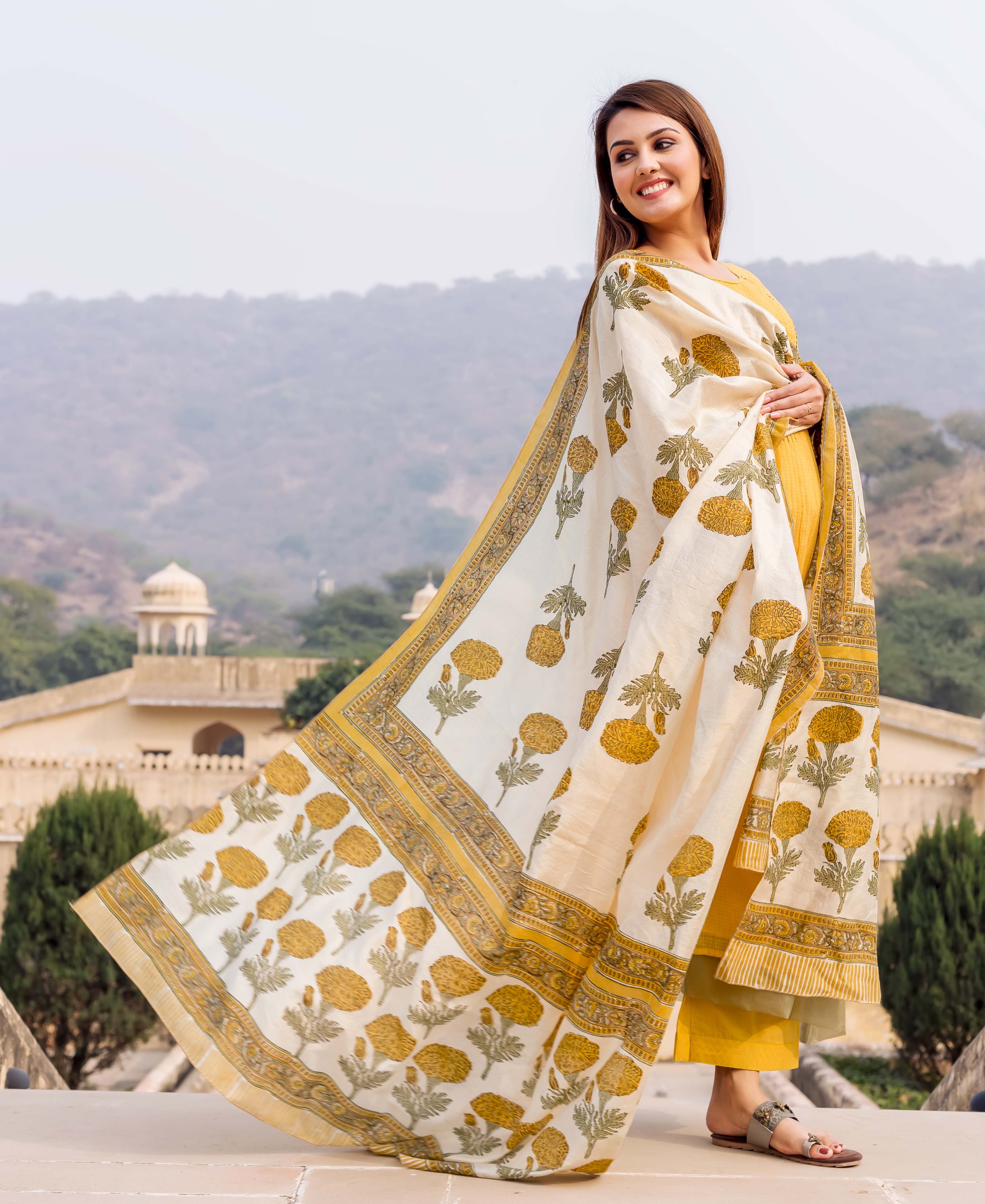 Woman in a yellow suit with a flowing white and yellow hand block printed dupatta.