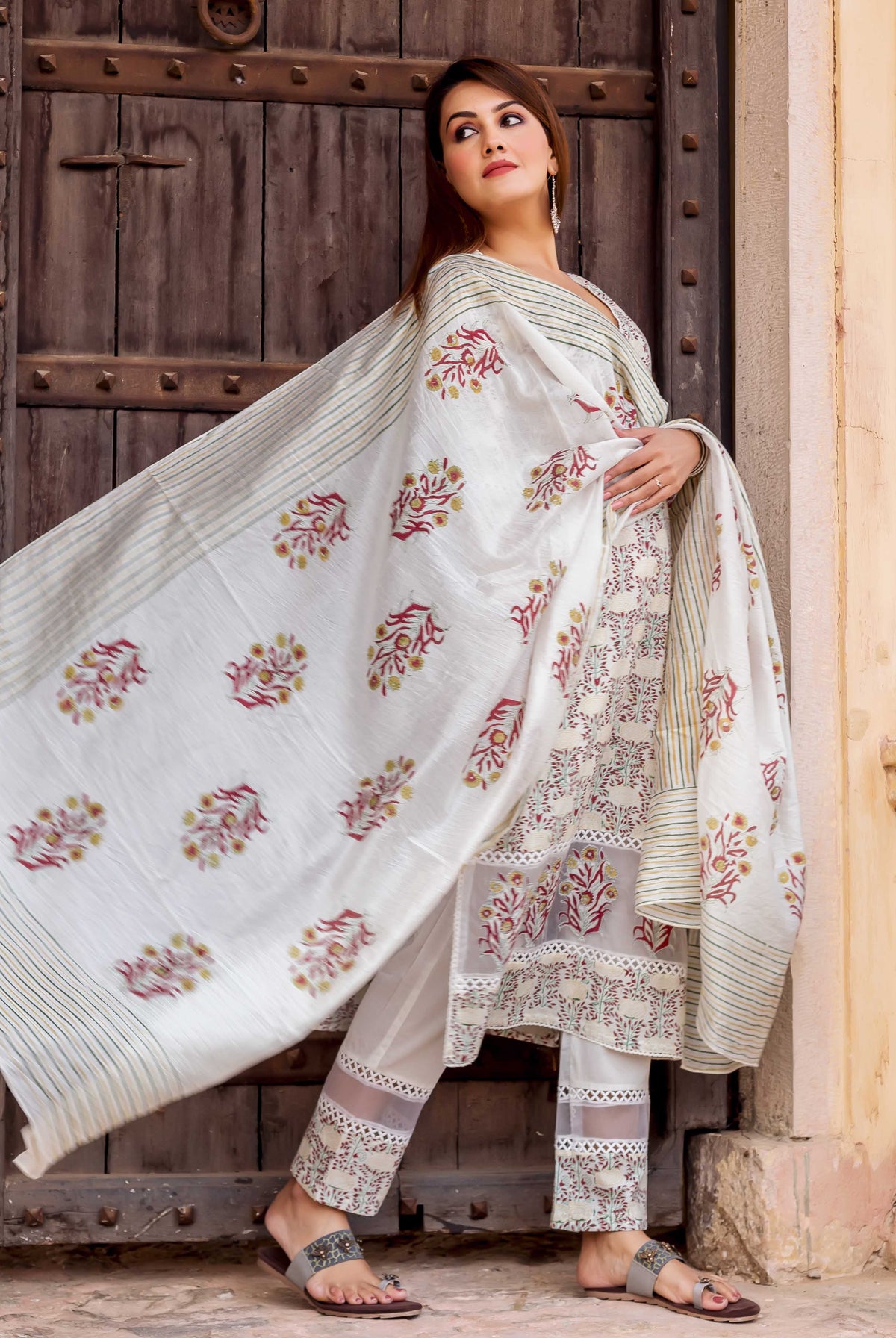 Woman in white hand block printed suit featuring a flowing dupatta with red and green florals.