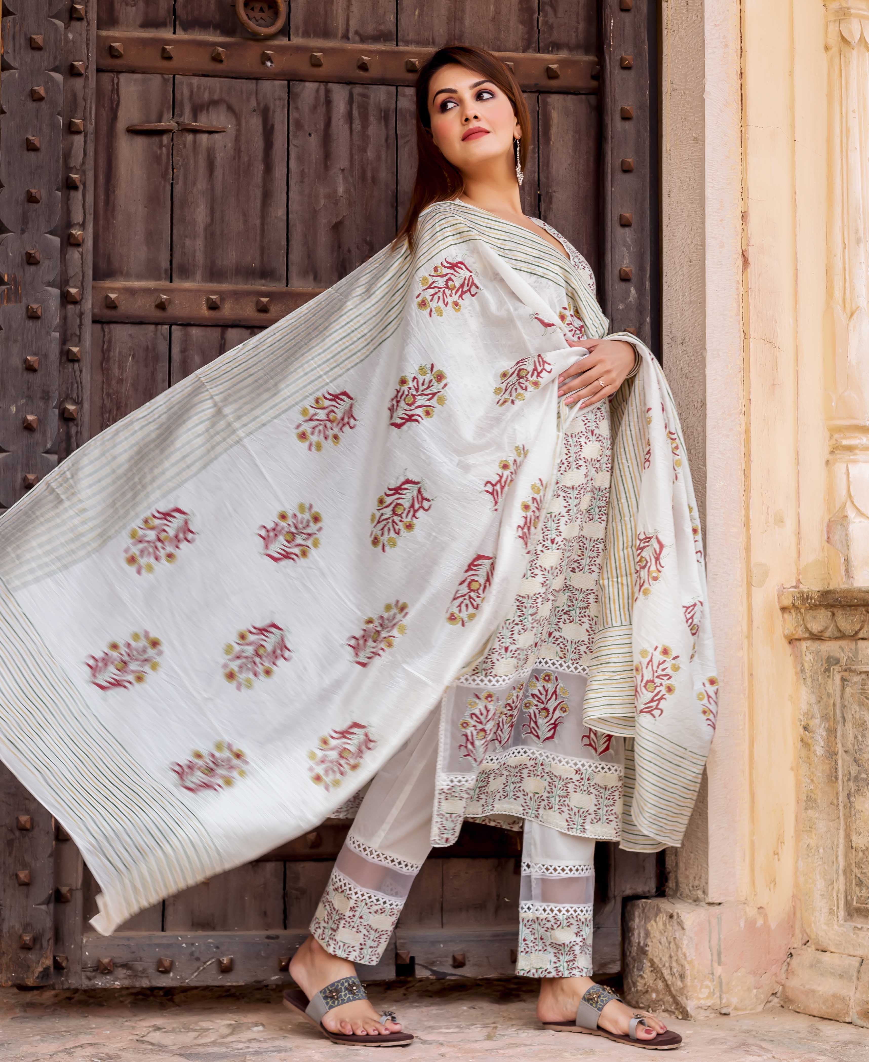 Woman in white hand block printed suit featuring a flowing dupatta with red and green florals.
