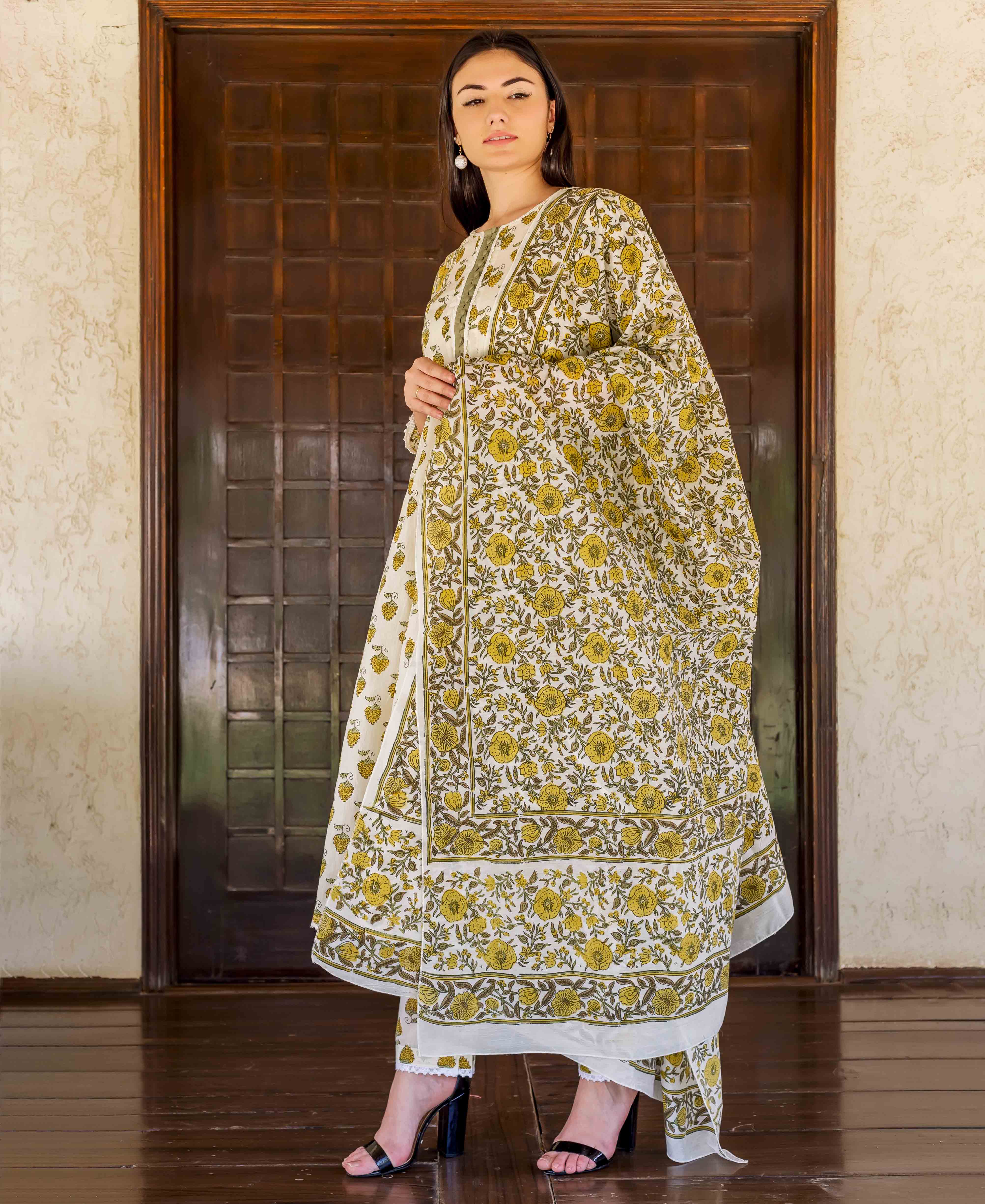 Full shot of a woman in a white and ochre yellow floral block print Chanderi suit.