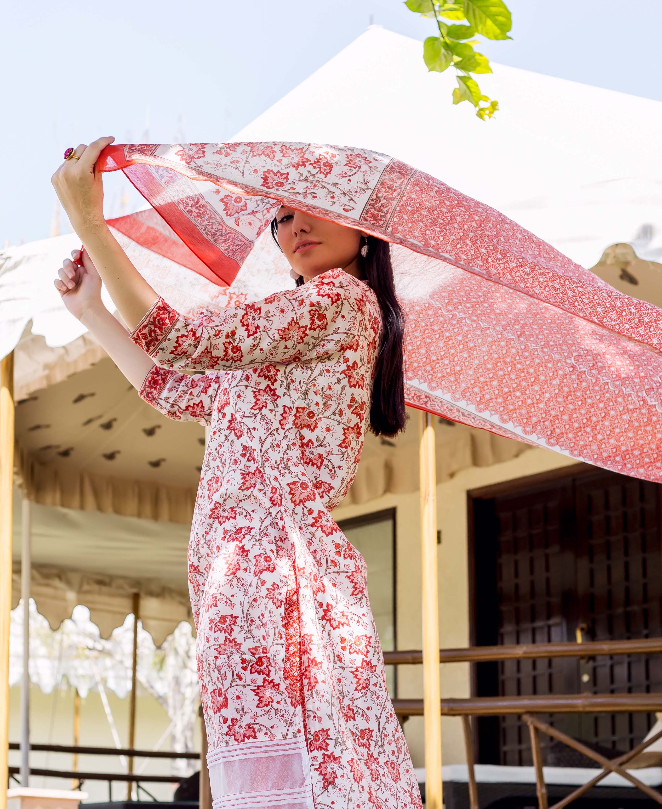 Model holds flowing peach and orange floral block-printed Chanderi dupatta and matching kurta.